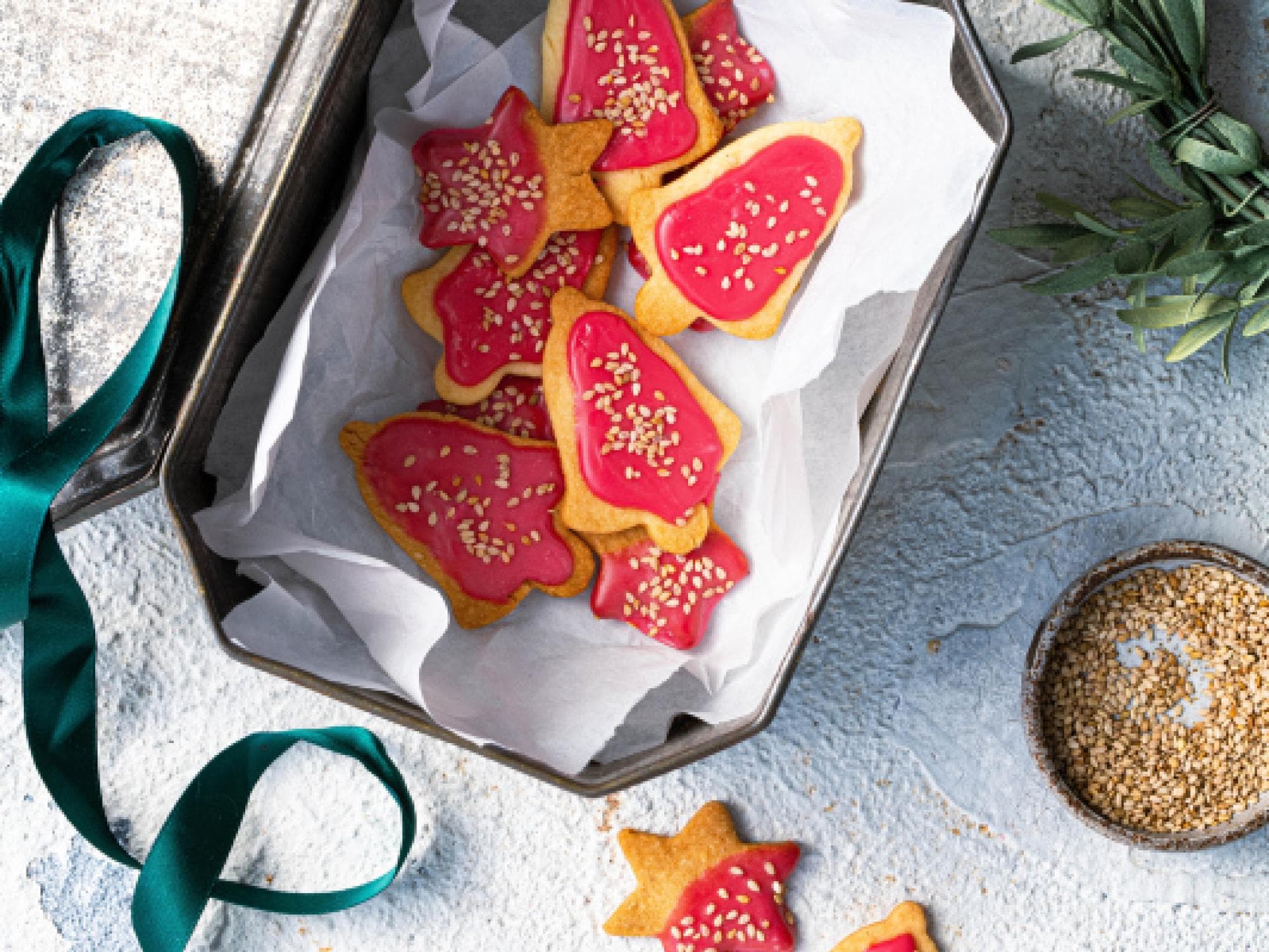 Weihnachtlich verzierte Sesamkekse in einer Blechkiste.
