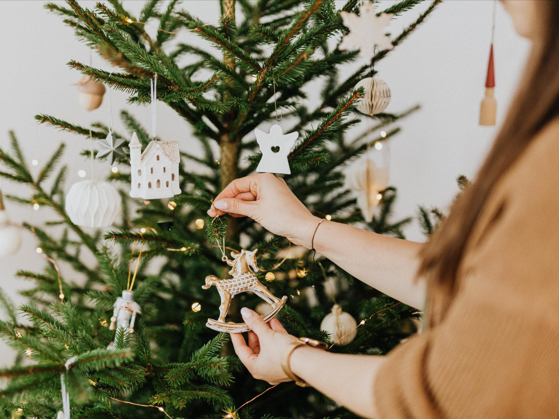 Weihnachtsbaumschmuck von H&M Home Frau schmückt Weihnachtsbaum mit Christbaumschmuck
