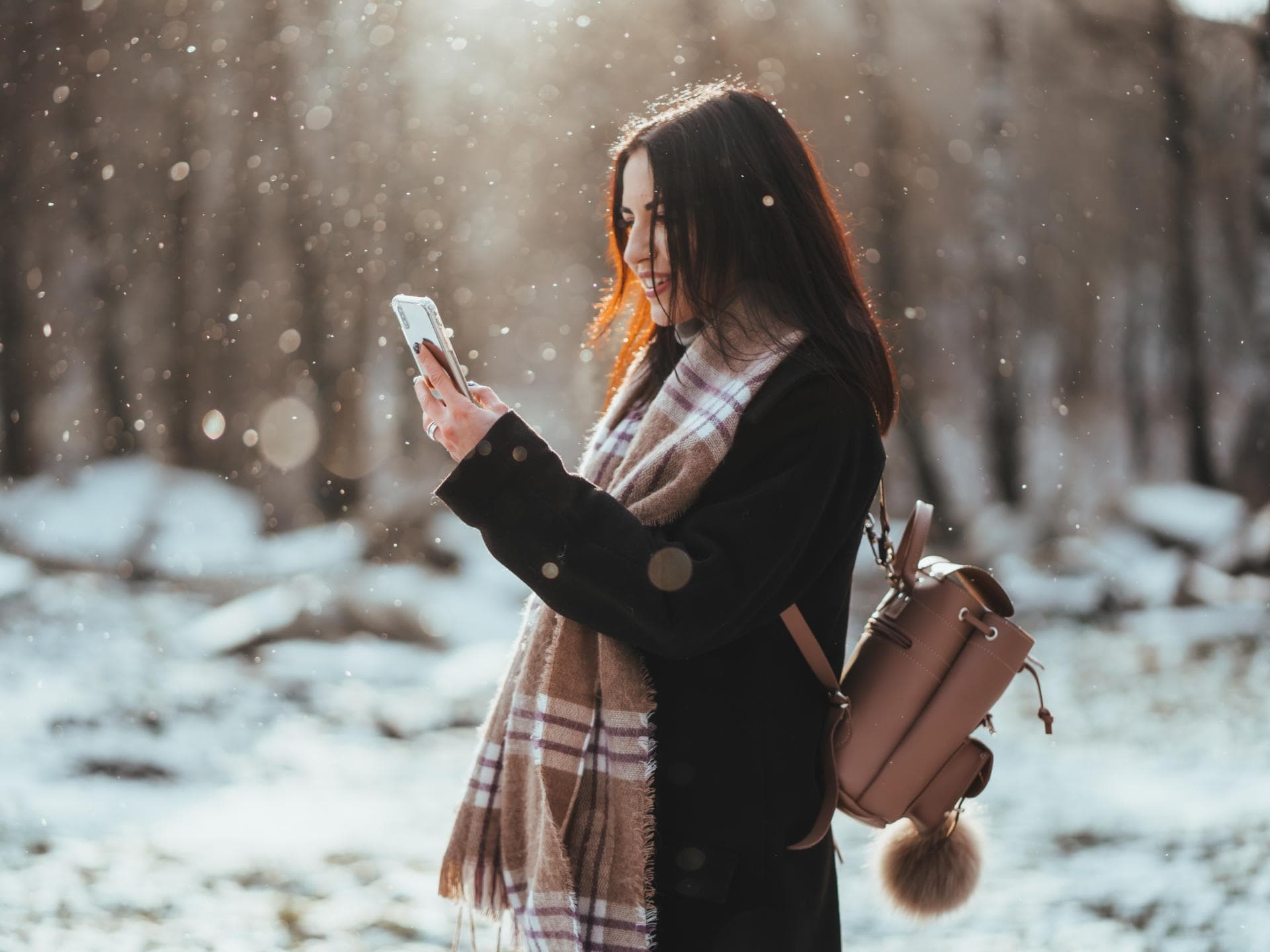 Frau hält Smartphone im Winter