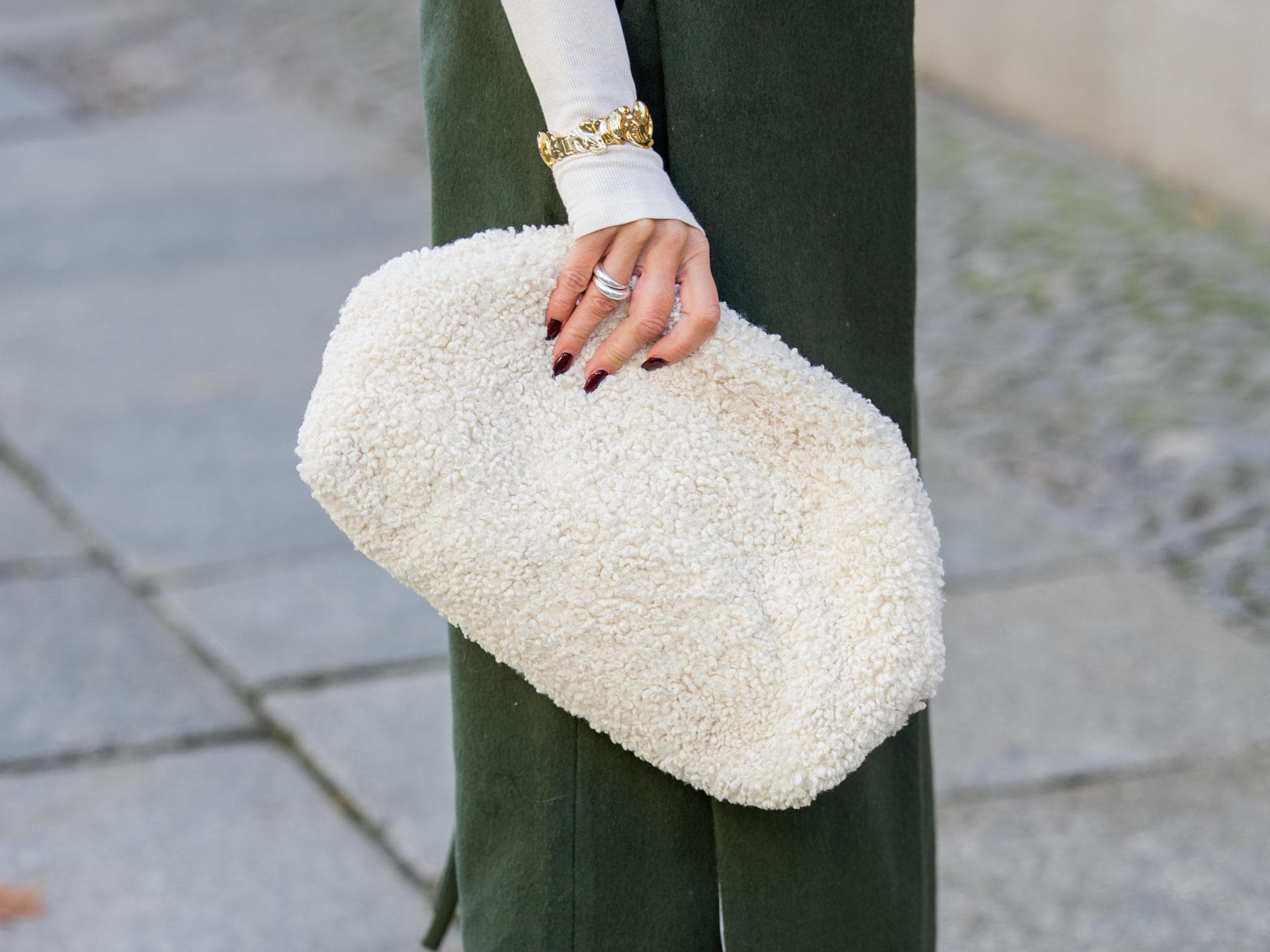 Frau hält eine weiße Teddytasche im eleganten Streetstyle. Frau hält eine weiße Teddytasche im eleganten Streetstyle.