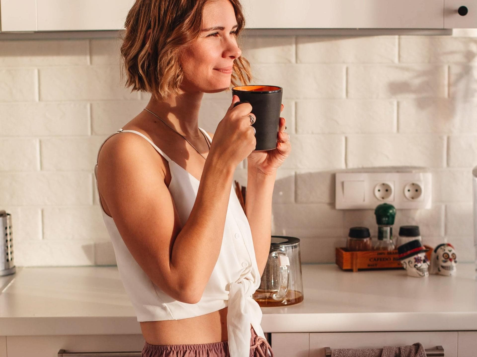 Frau trinkt Kaffee in der Küche.