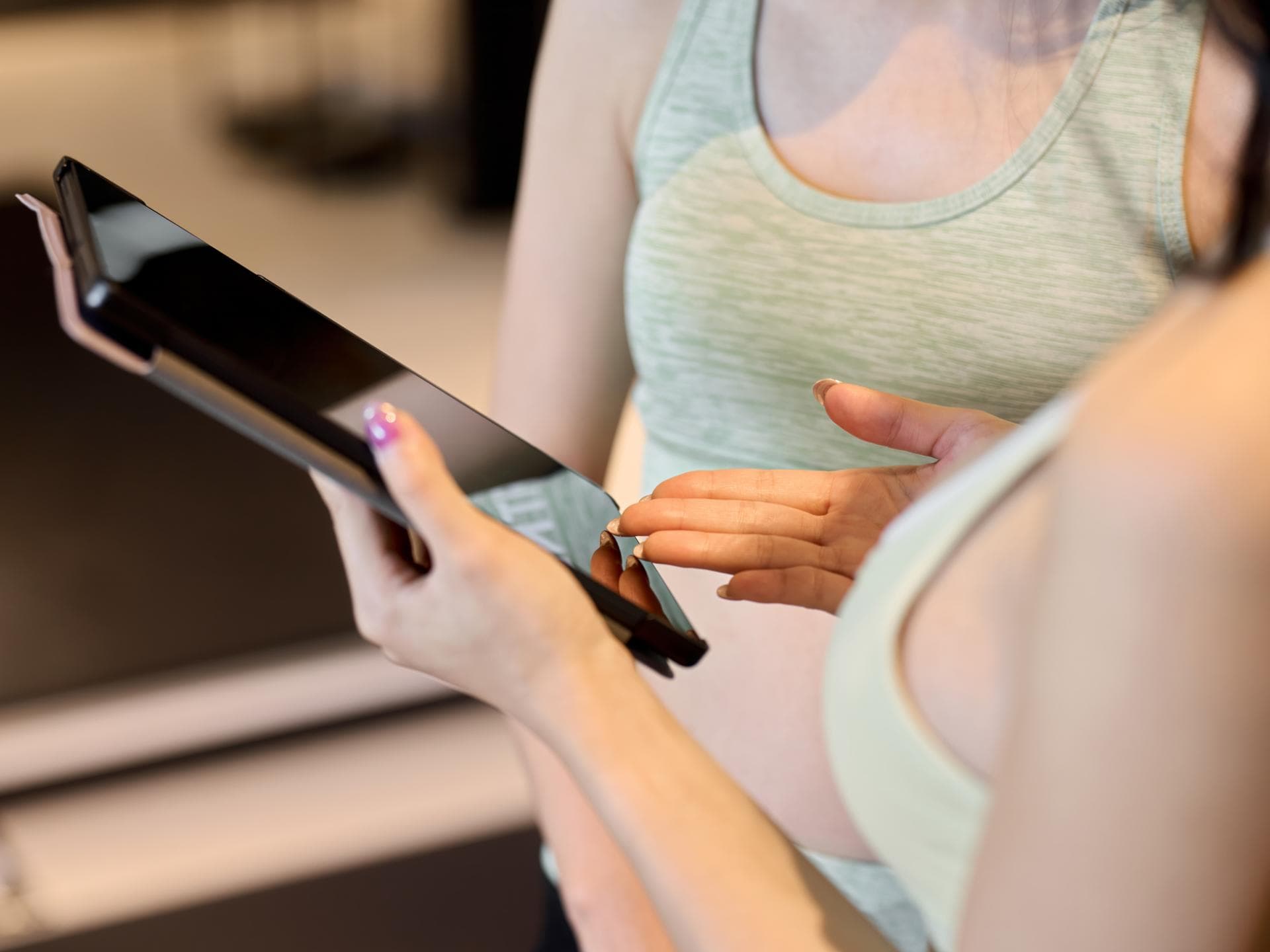 Frau zeigt kostenlose Trainingspläne auf dem Tablet