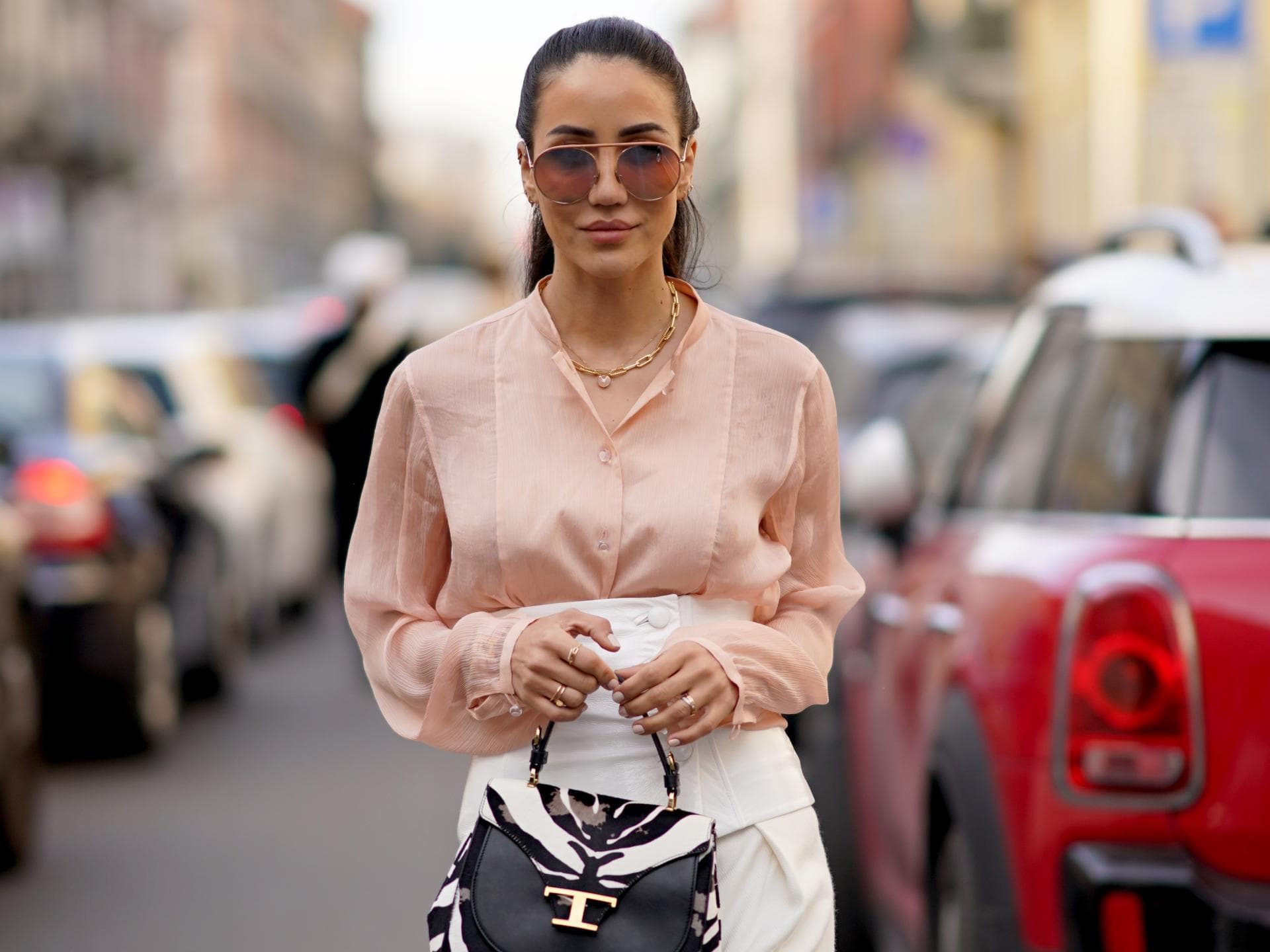 Frau im eleganten Streetstyle mit einer Bluse in der Farbe Peach Fuzz. Frau im eleganten Streetstyle mit einer Bluse in der Farbe Peach Fuzz.