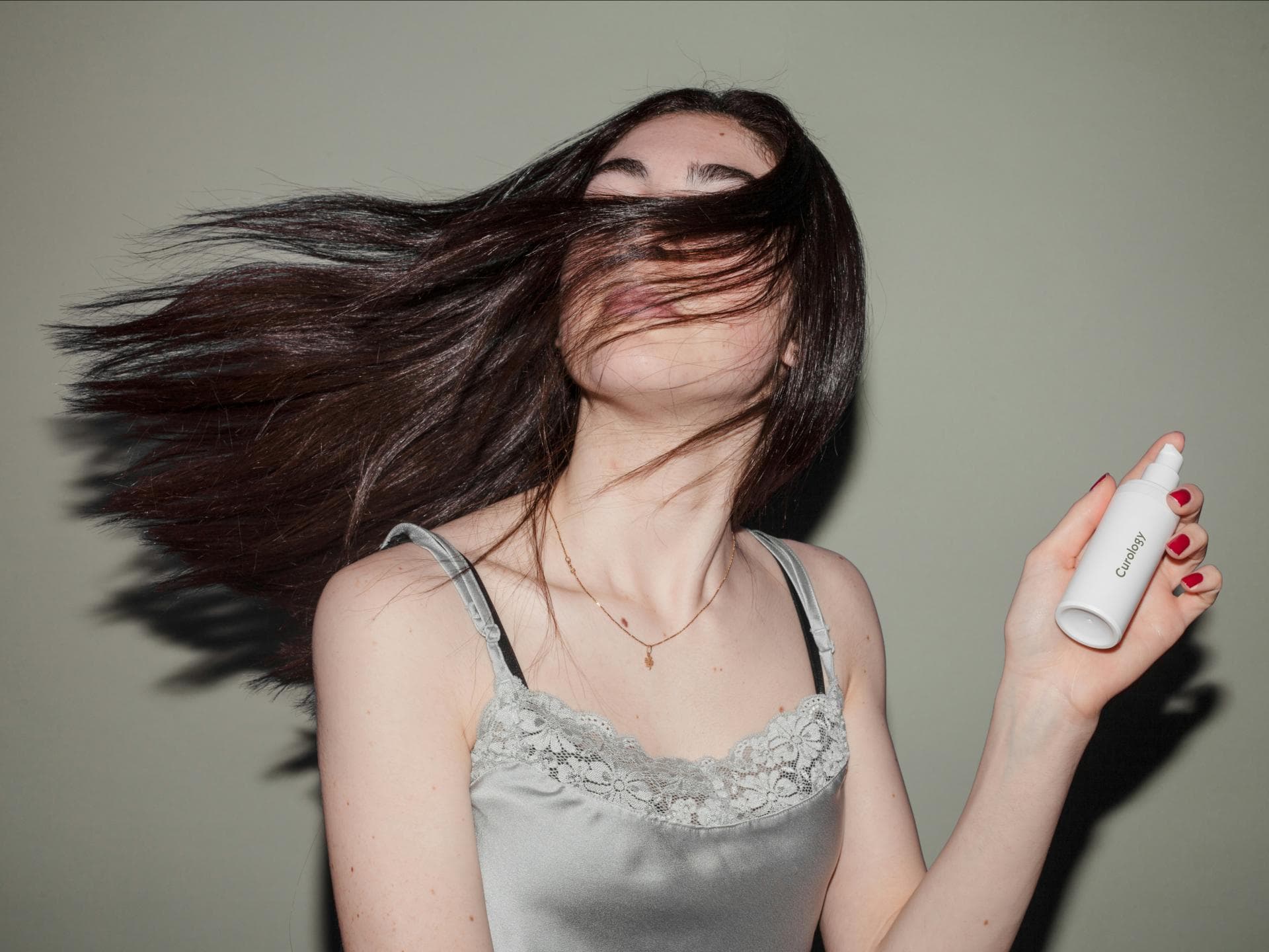 Frau hält pflegendes Haarspray