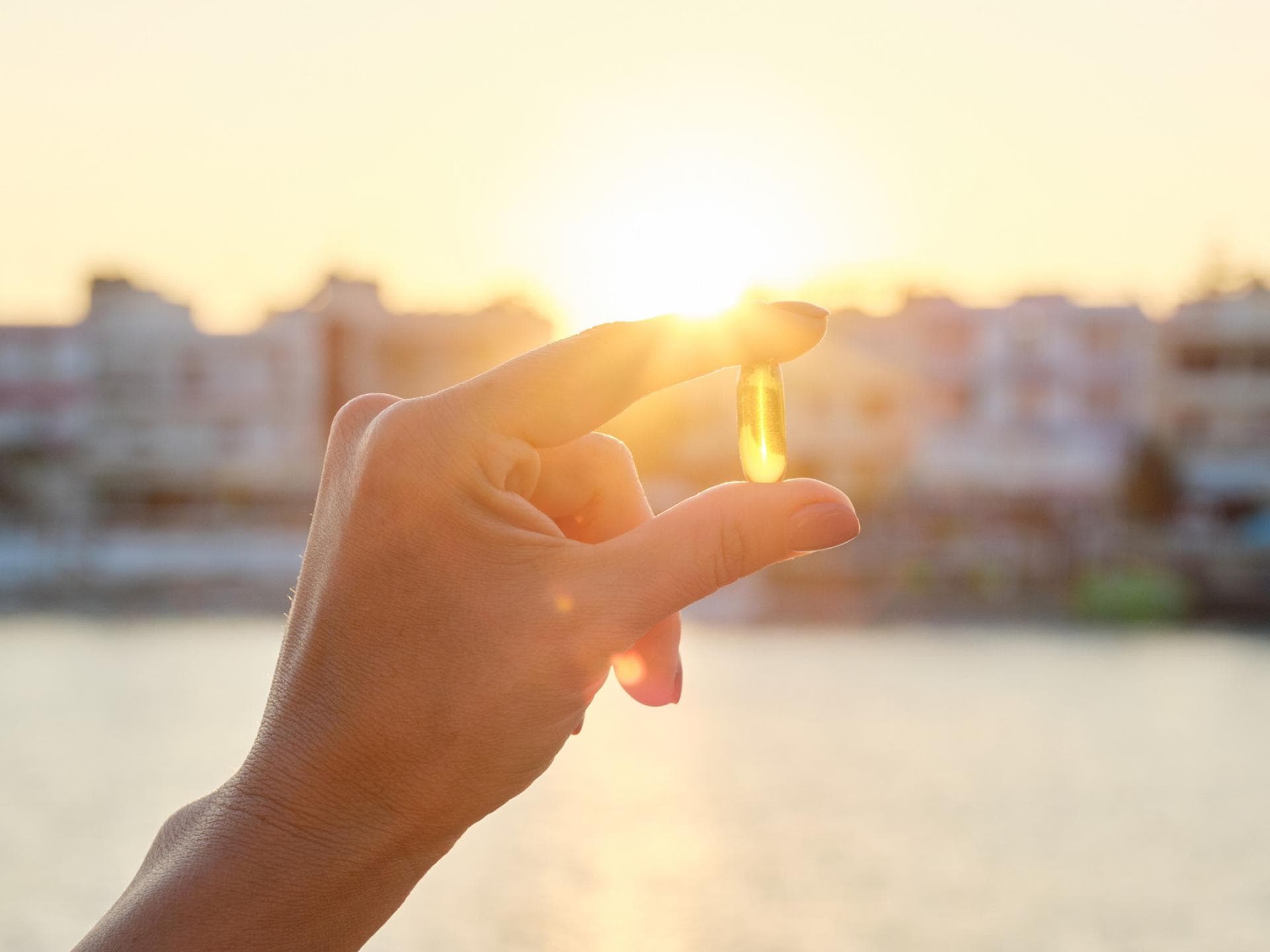 Vitamin D Kapsel zwischen den Fingern Vitamin D Kapsel zwischen den Fingern