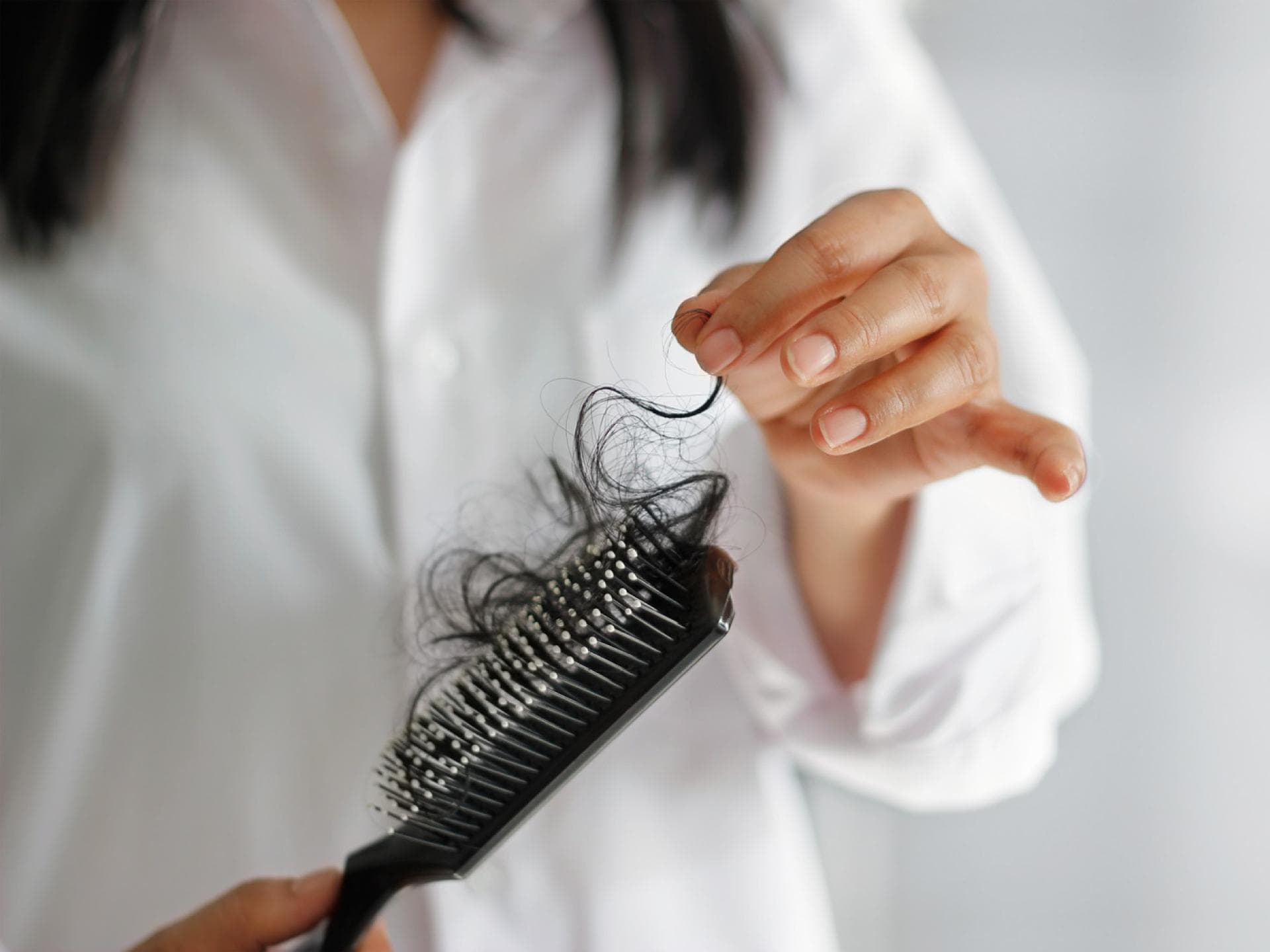 Frau zieht Haare aus der Haarbürste