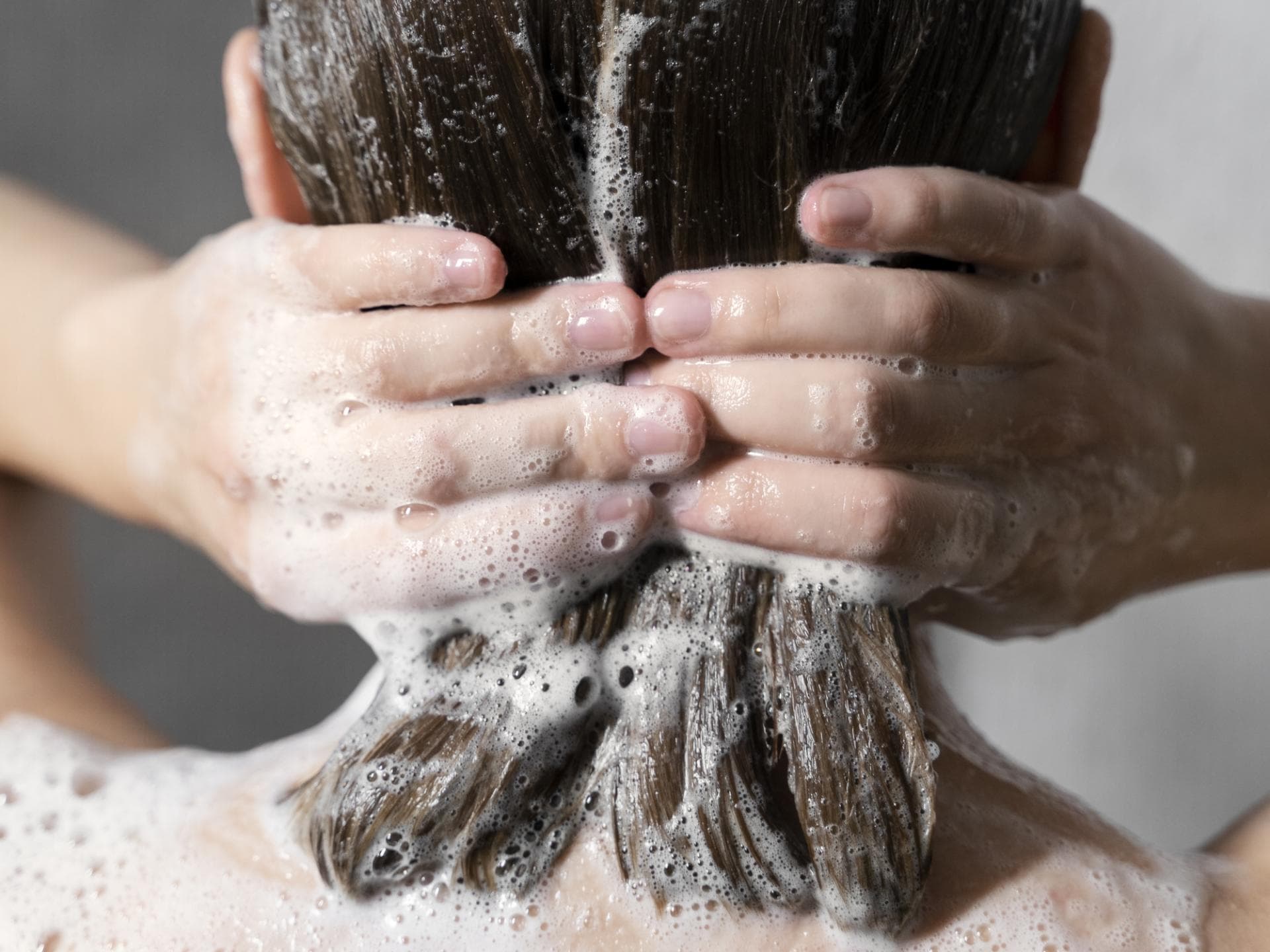 Frau wäscht Haare unter der Dusche