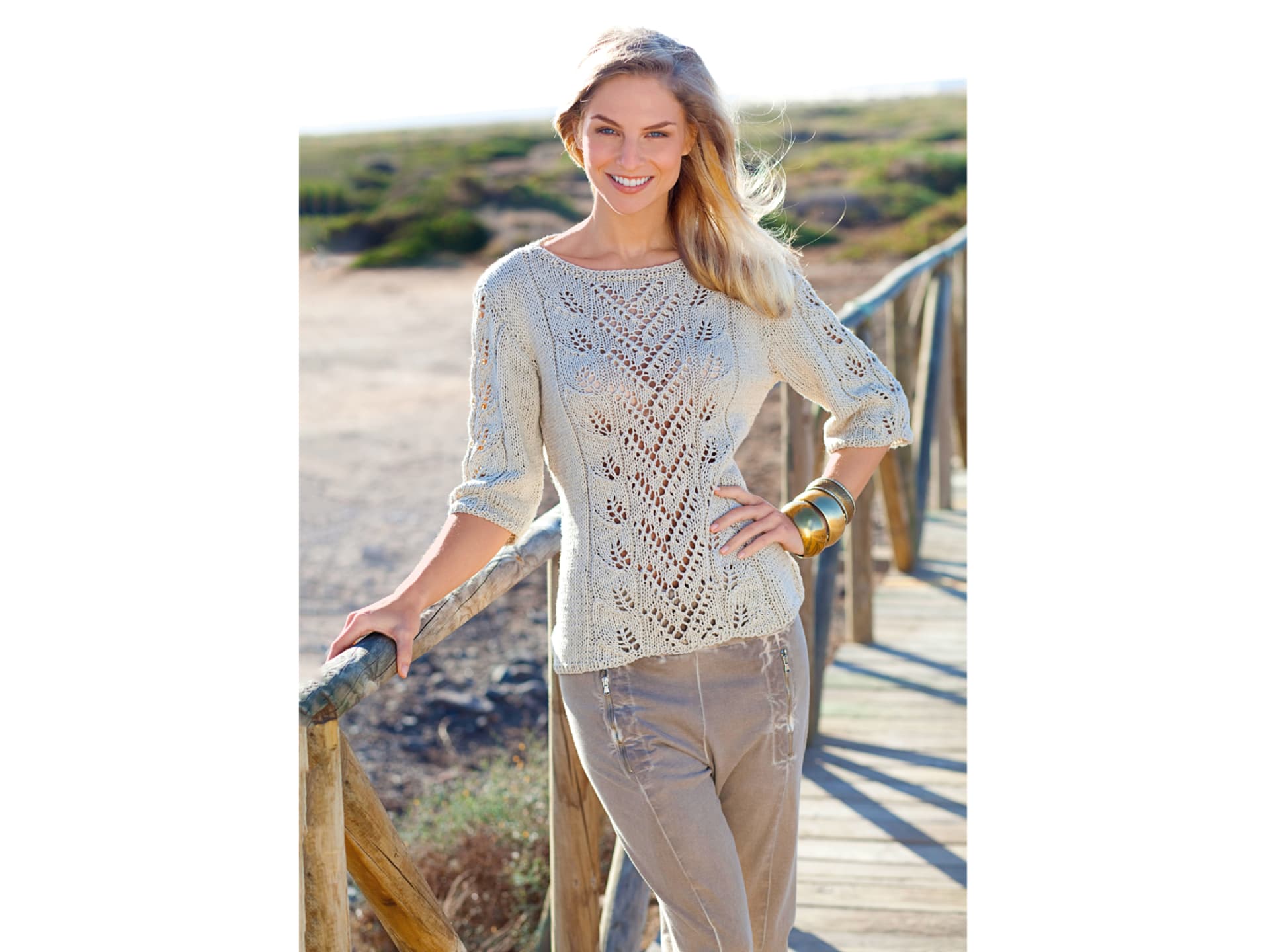 Model in beigem Lochmuster-Pullover mit Blattmuster