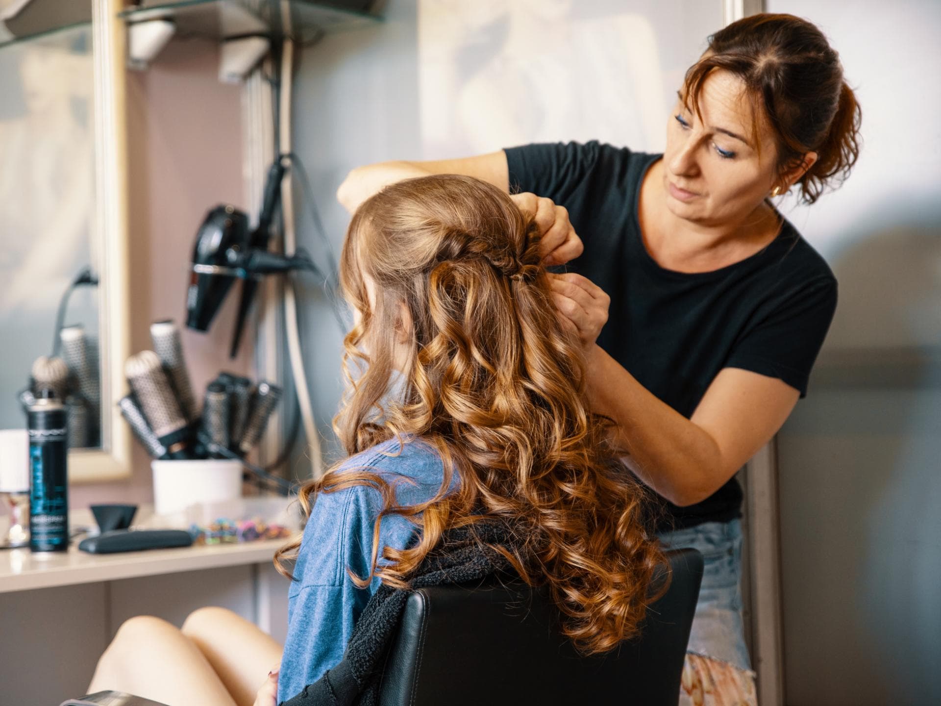 Frau macht einer anderen Frau eine festliche Frisur mit Locken