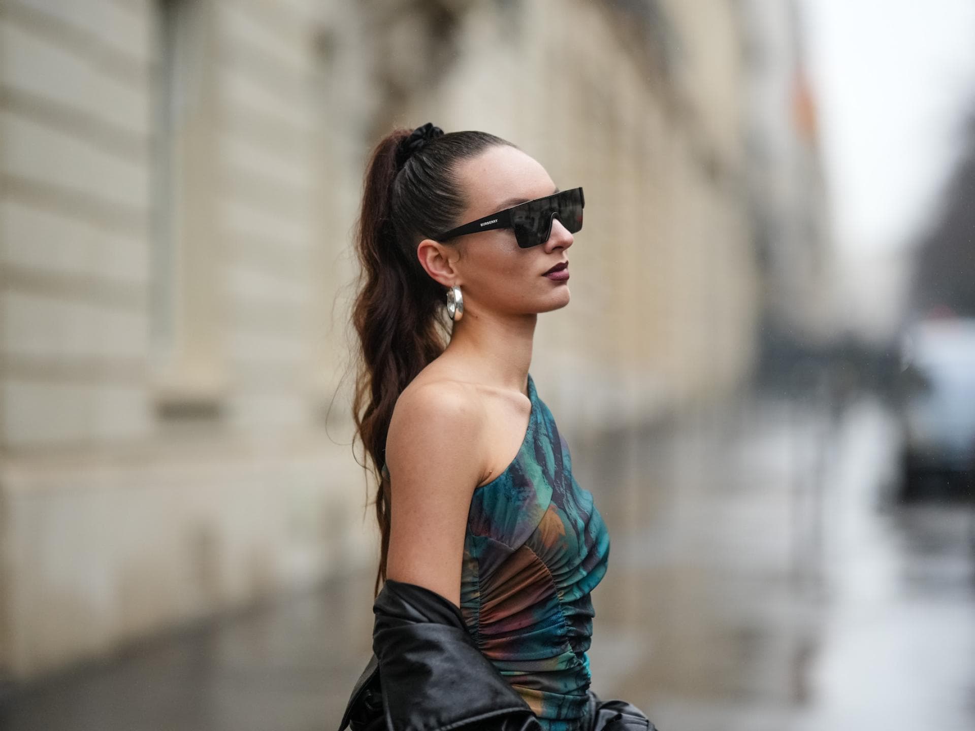 Ein hoher Zopf zählt zu beliebten Frisuren bei Regen. Frau mit hohem Zopf und Sonnenbrille