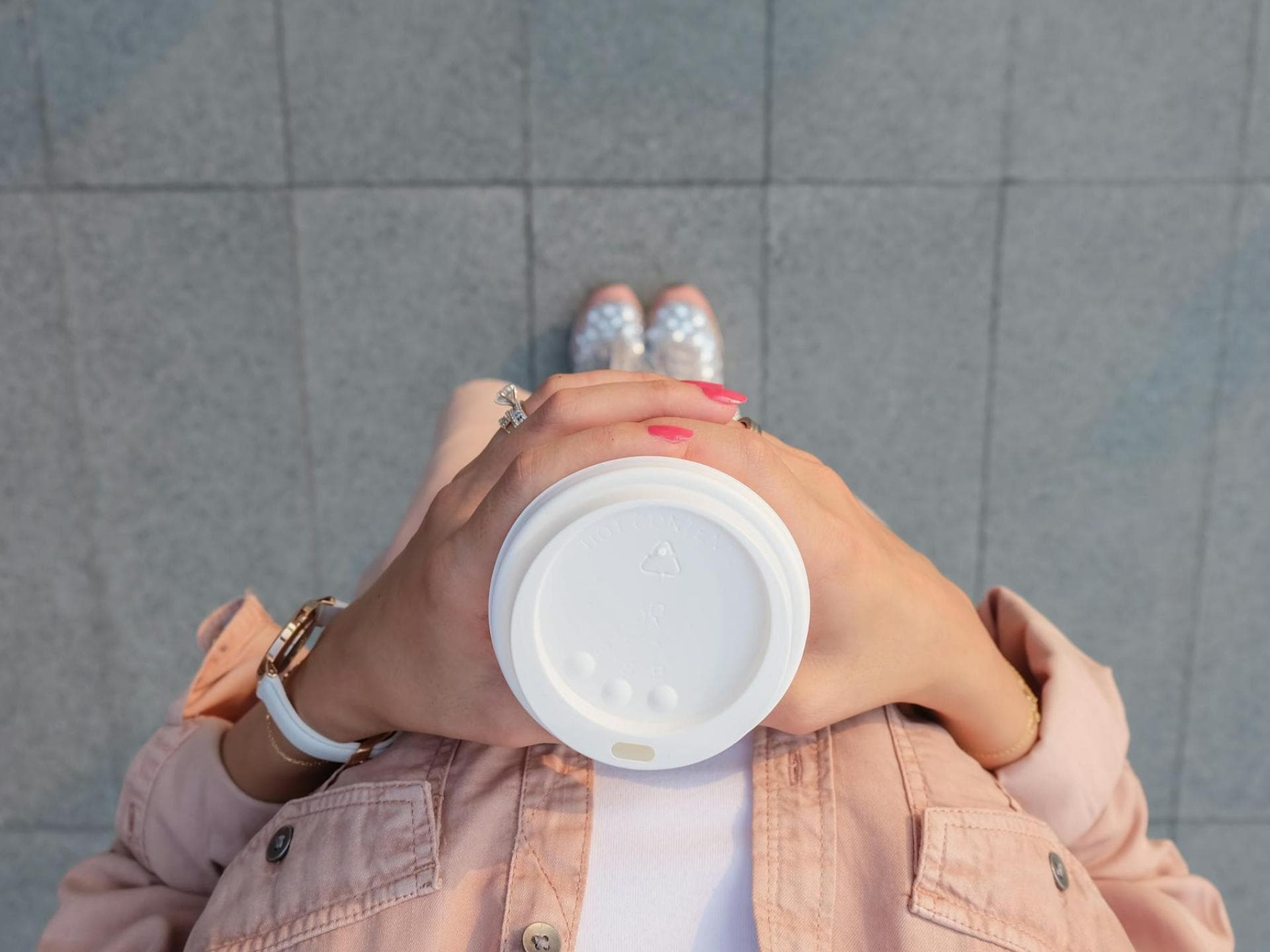 Frau hält einen Kaffeebecher in ihren Händen.