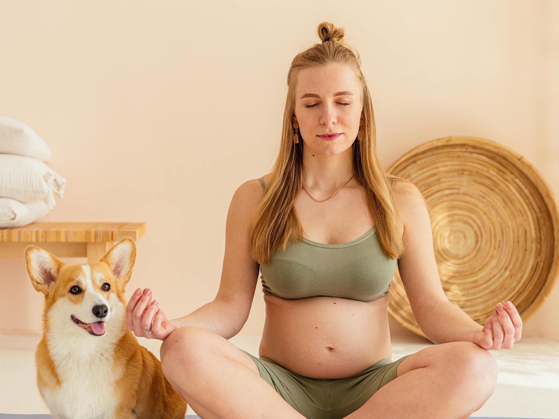 Frau auf einer Matte in einer Yoga-Position mit einem Hund daneben.