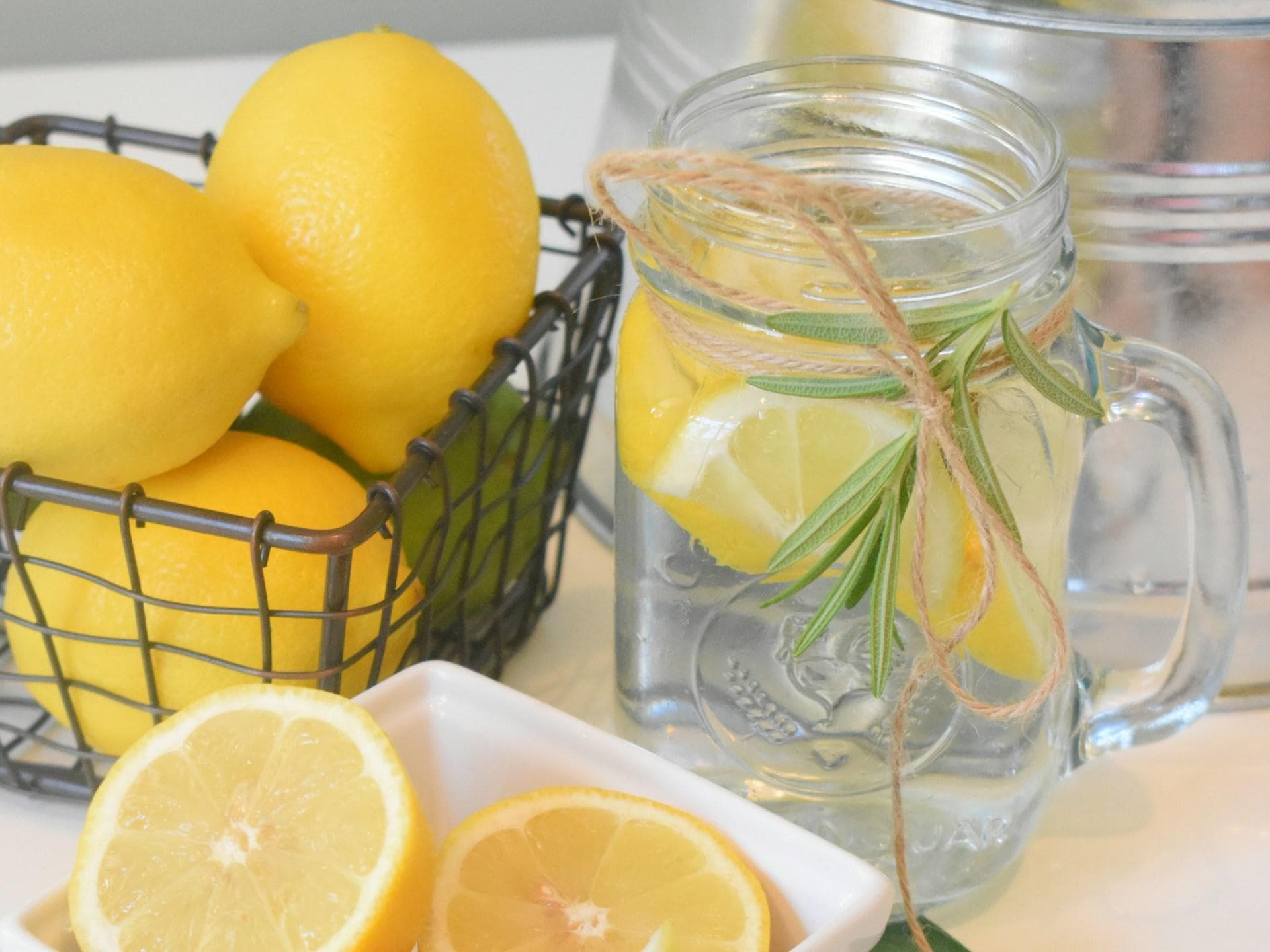 Zitronenwasser ist durchaus gesund und liefert viele Vitamine. Zitronen und ein Glas mit Wasser und Zitronenscheiben