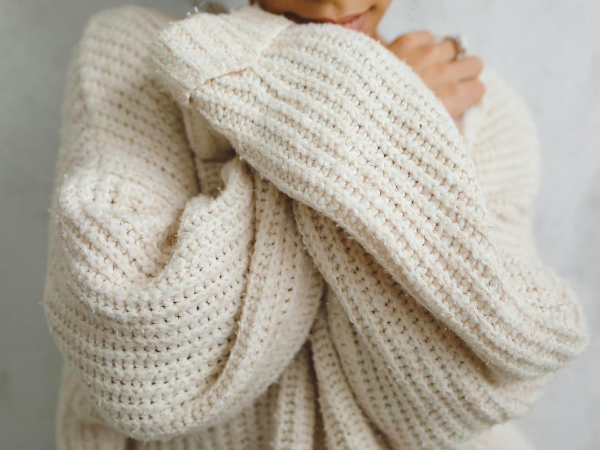 Beim Stricken für den Herbst und Winter kommt es auf die richtige Wolle an Eine Frau trägt einen selbst gestrickten Pullover aus warmer Wolle