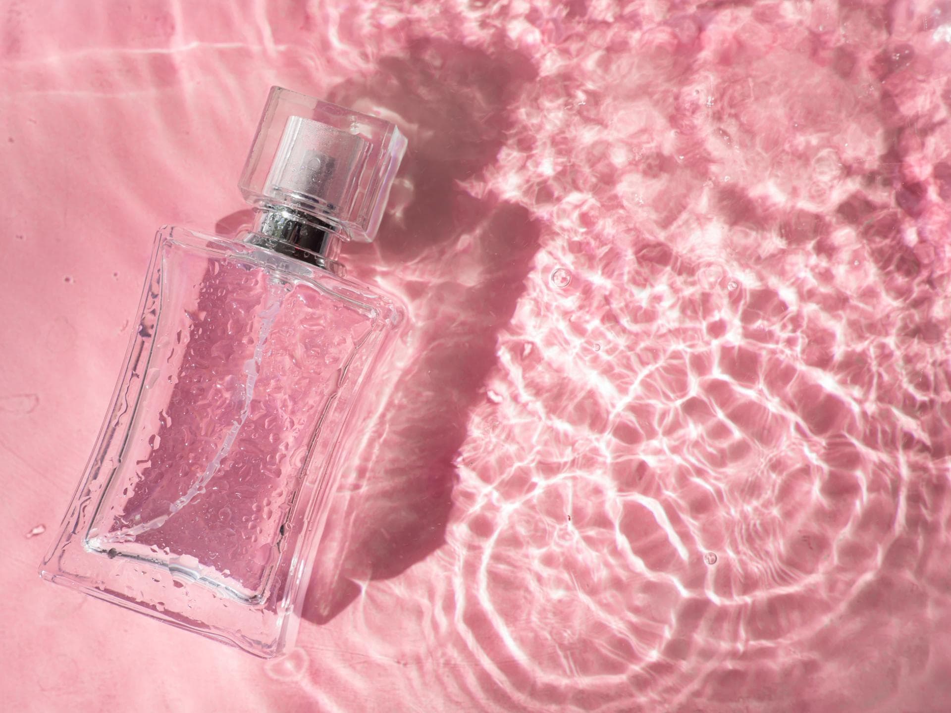 Ein Parfumflakon in seichtem Wasser liegend