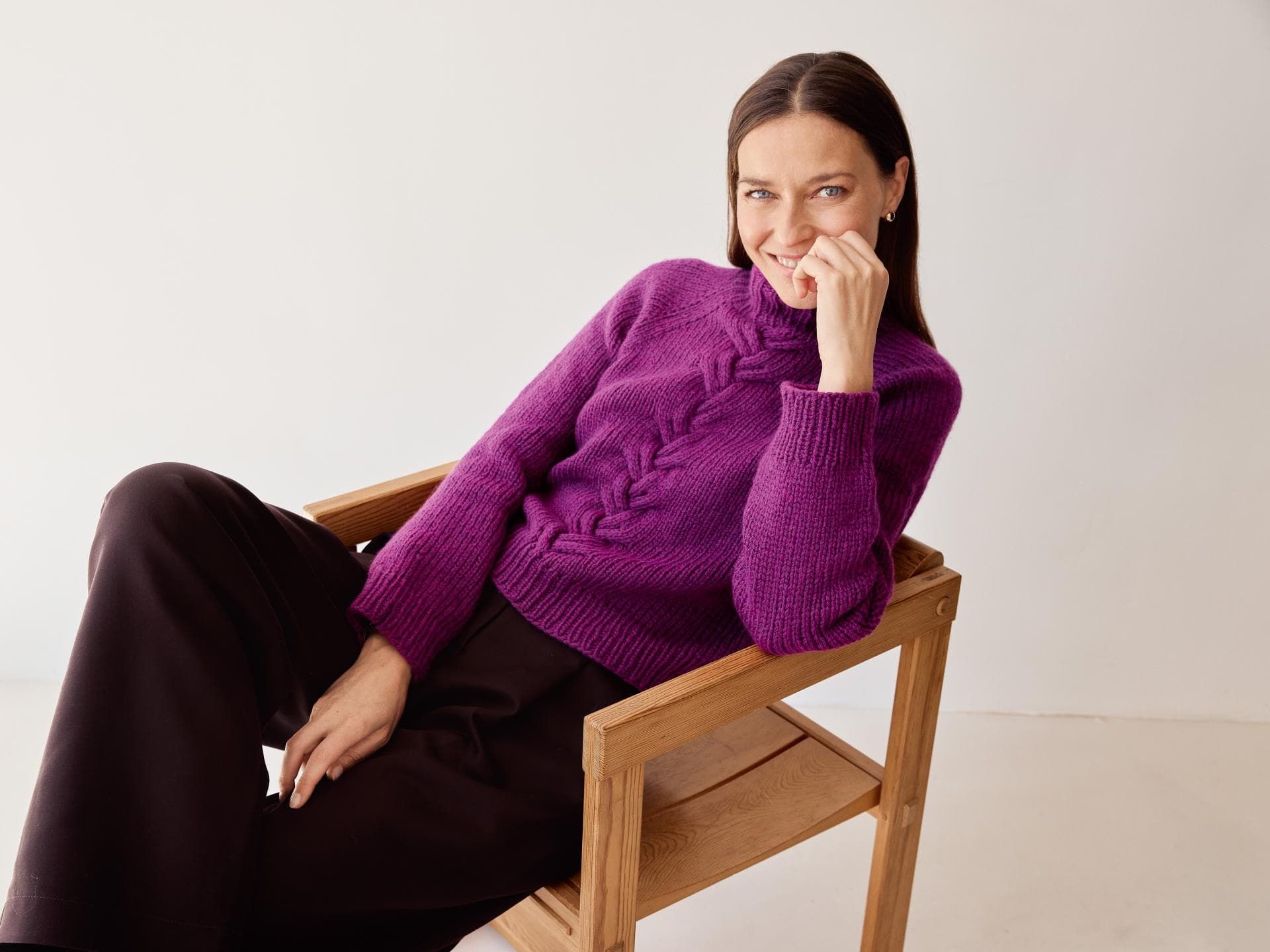 Model in fuchsiafarbenem Zopfmuster-Rollkragenpullover von Lana Grossa