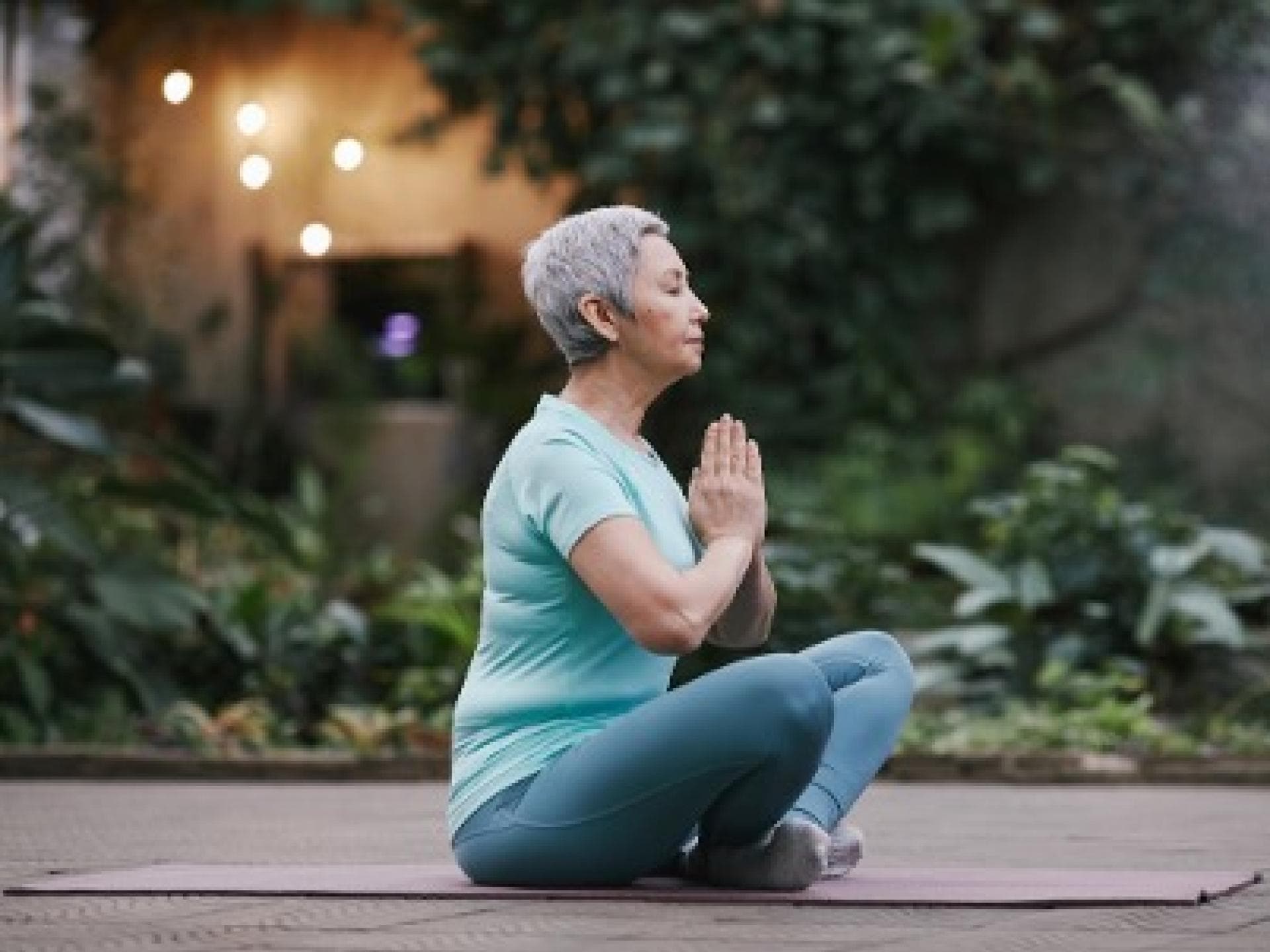 Eine ältere Frau macht Yoga im Freien