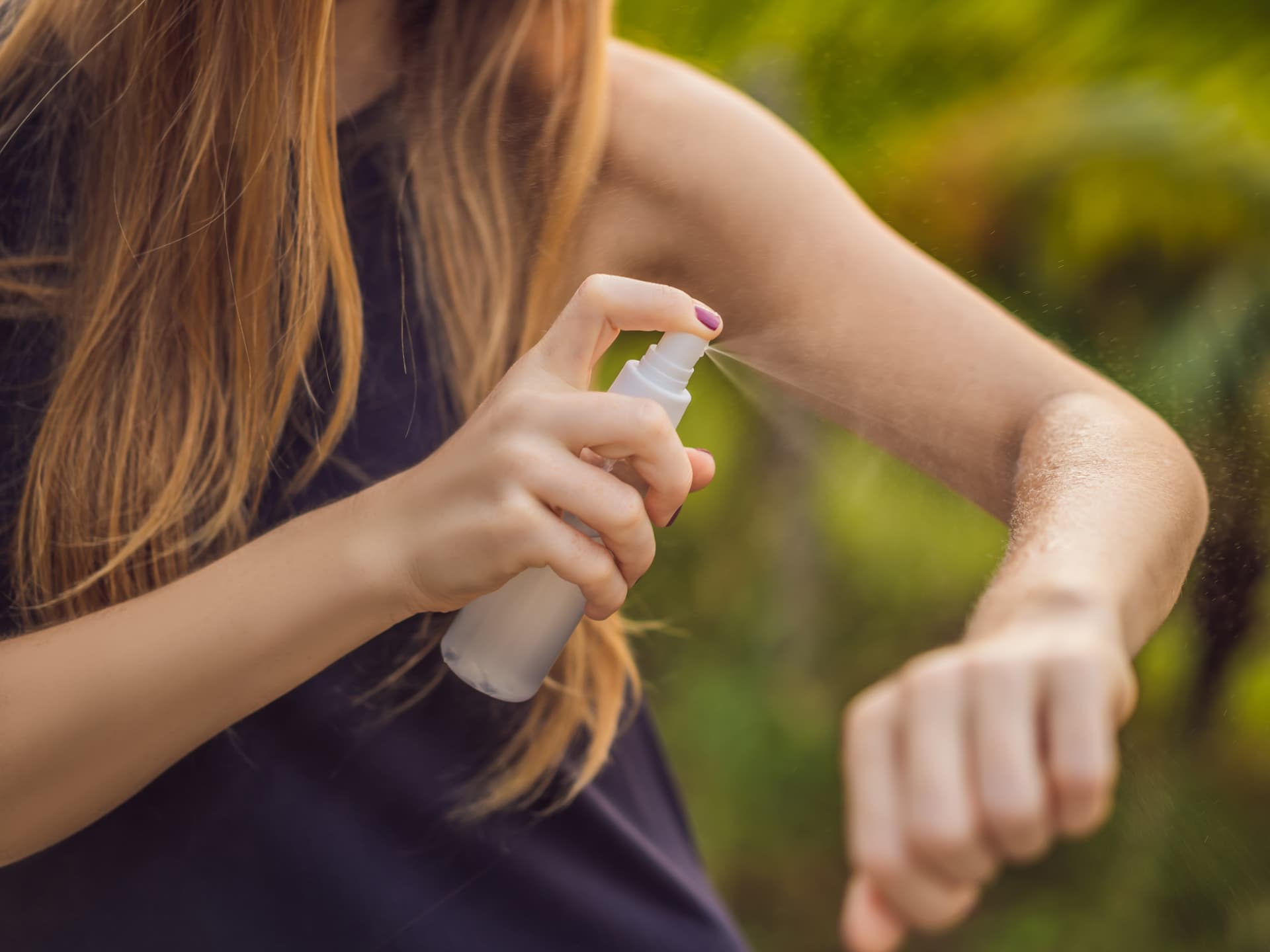 Frau sprüht sich mit selbst gemachtem Zeckenspray ein