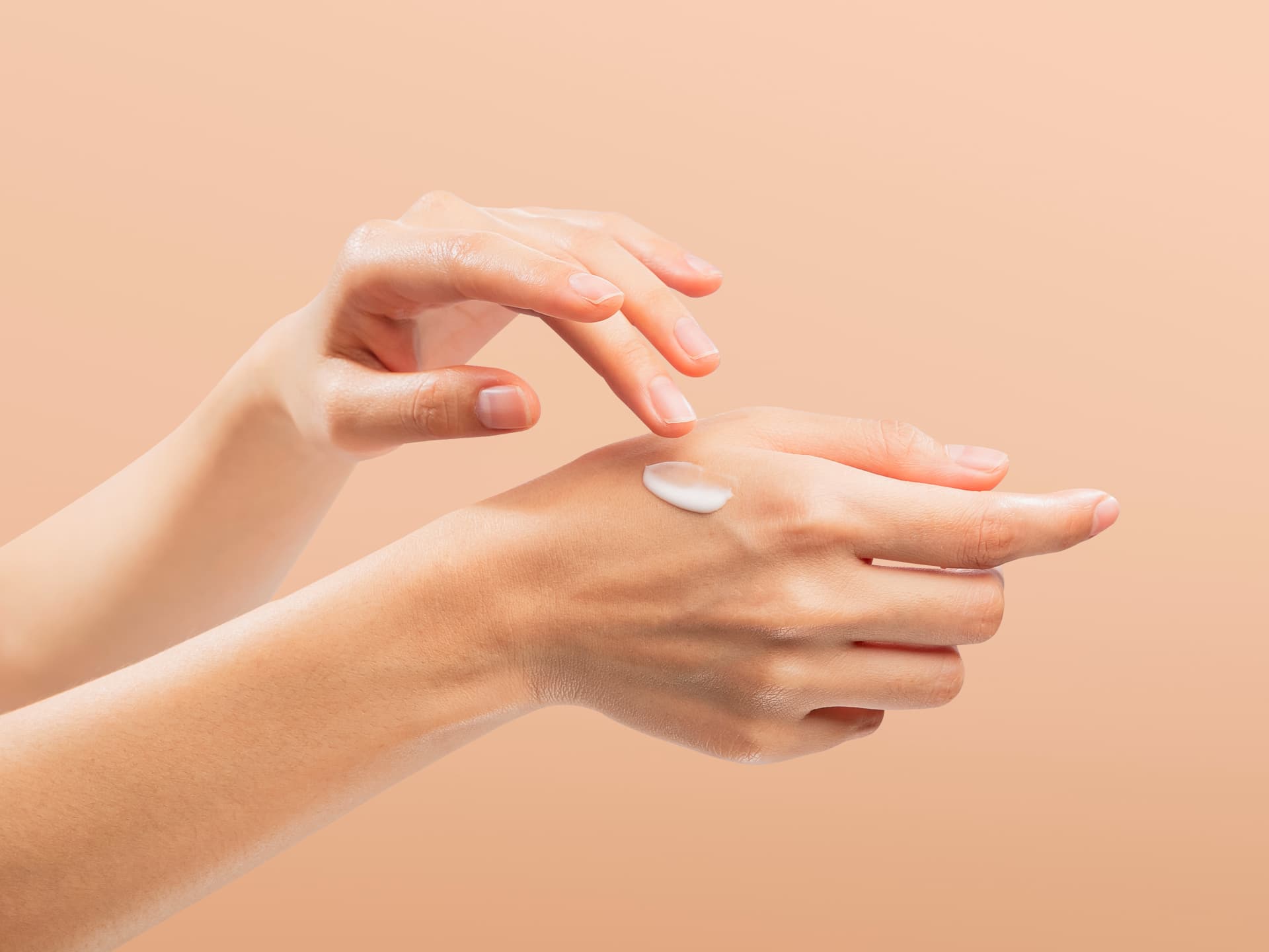 Handcreme mit Sonnenschutz schützt vor vorzeitiger Hautalterung Frau trägt Handcreme mit Sonnenschutz auf ihre Hände auf