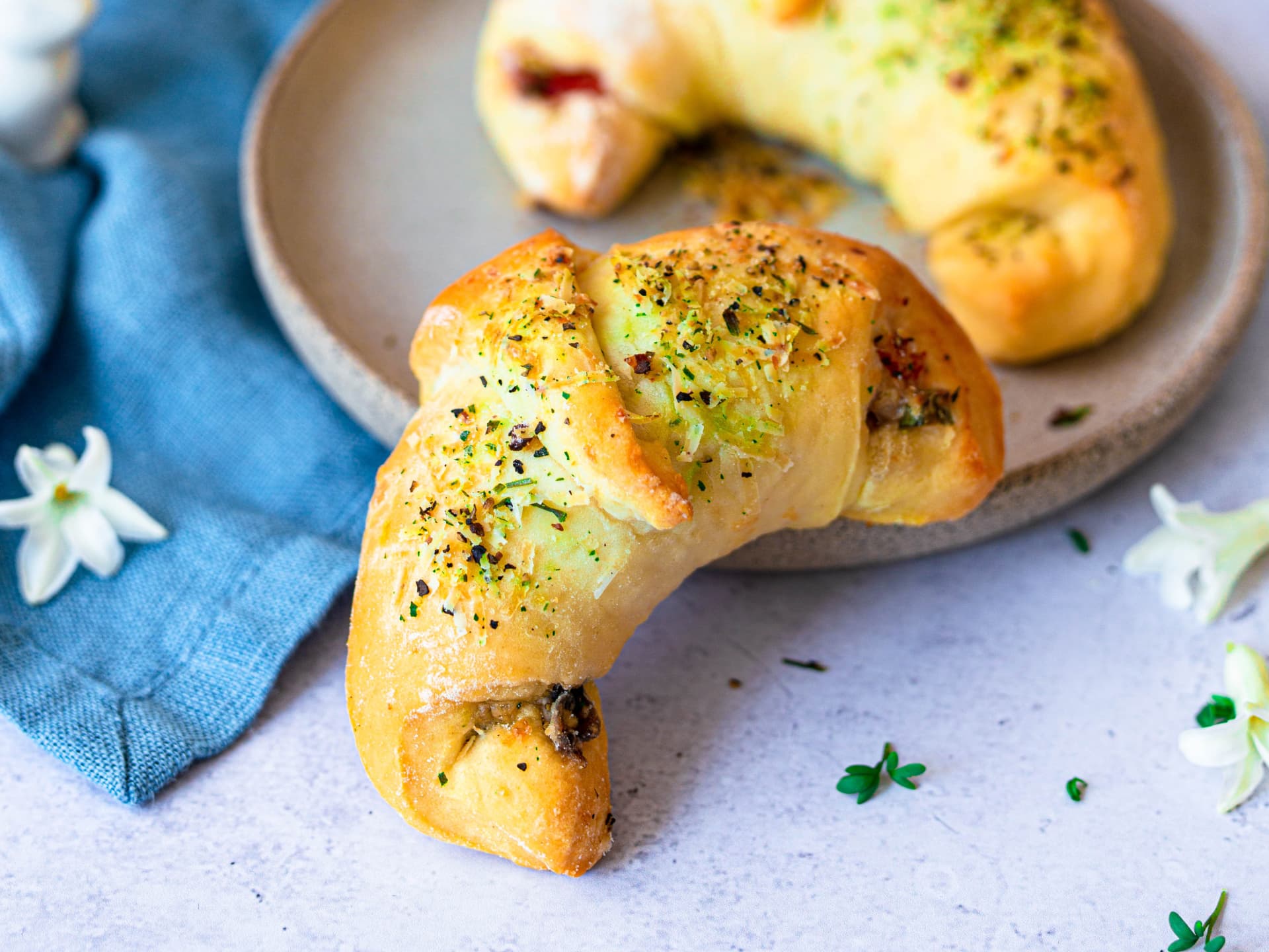 Pizzateig-Croissants mit Käse-Gewürz-Topping neben einem Teller angerichtet 