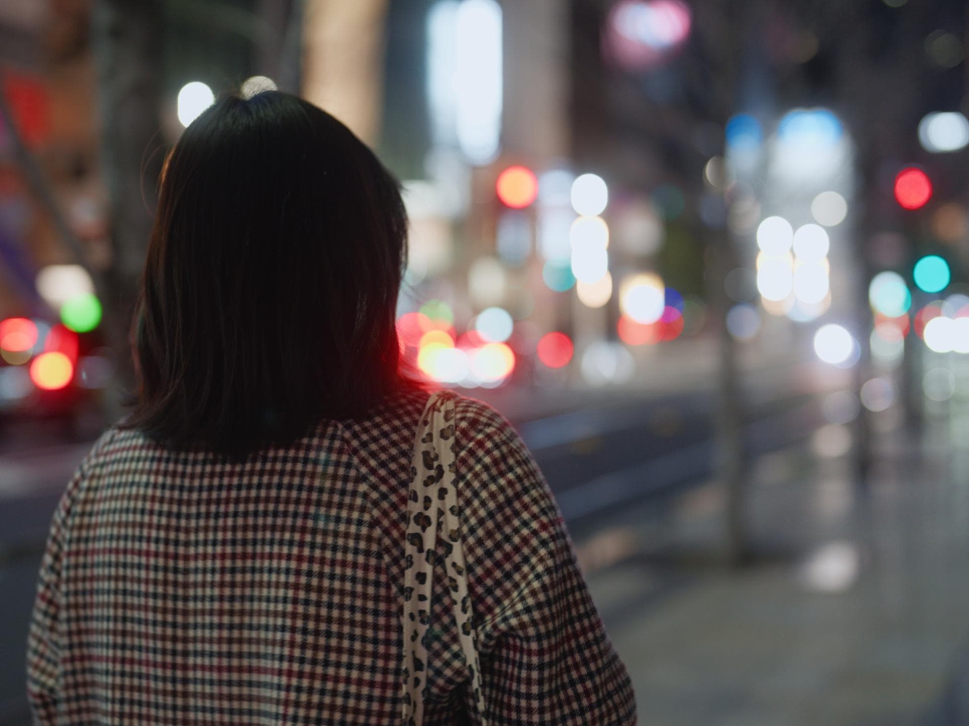 Gesetz gegen Catcalling - Interview mit Juristin Dr. Carolin Weyand Eine Frau spaziert allein durch eine große, hellbeleuchtet Stadt. Sie kerht uns ihren Rücken zu und trägt einen karierten Herbstmantel.