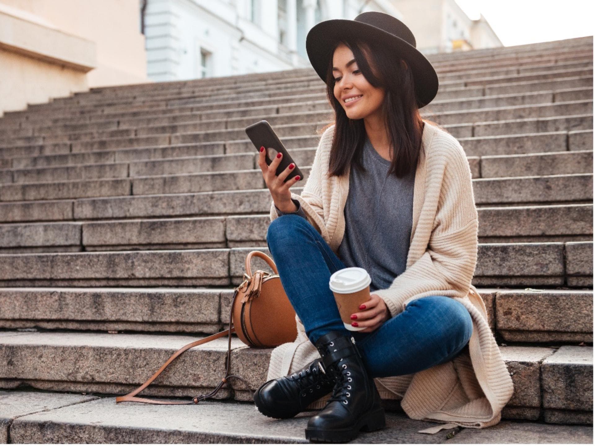 Frau sitzt auf einer Treppe und scrollt am Smartphone