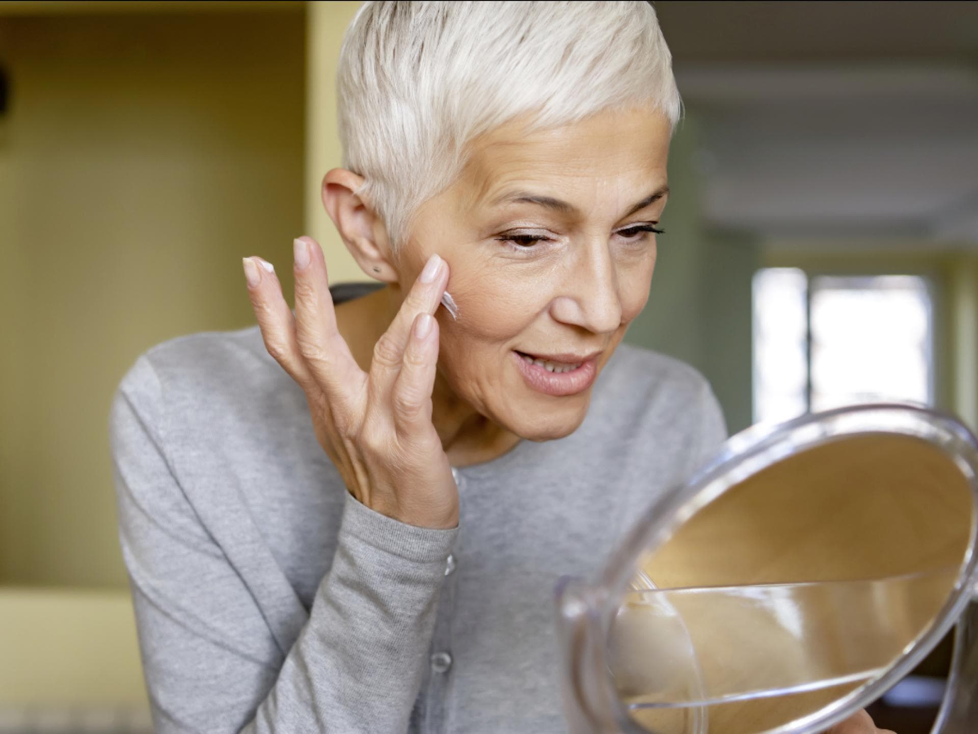 Reife Frau benutzt Anti-Aging-Produkte