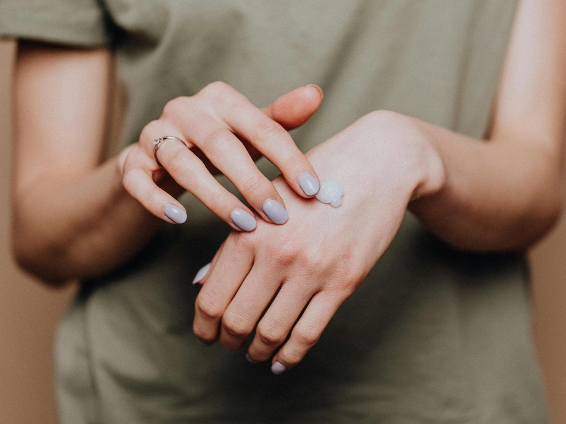 Frau, die Handcreme mit einer Hand auf der anderen verteilt