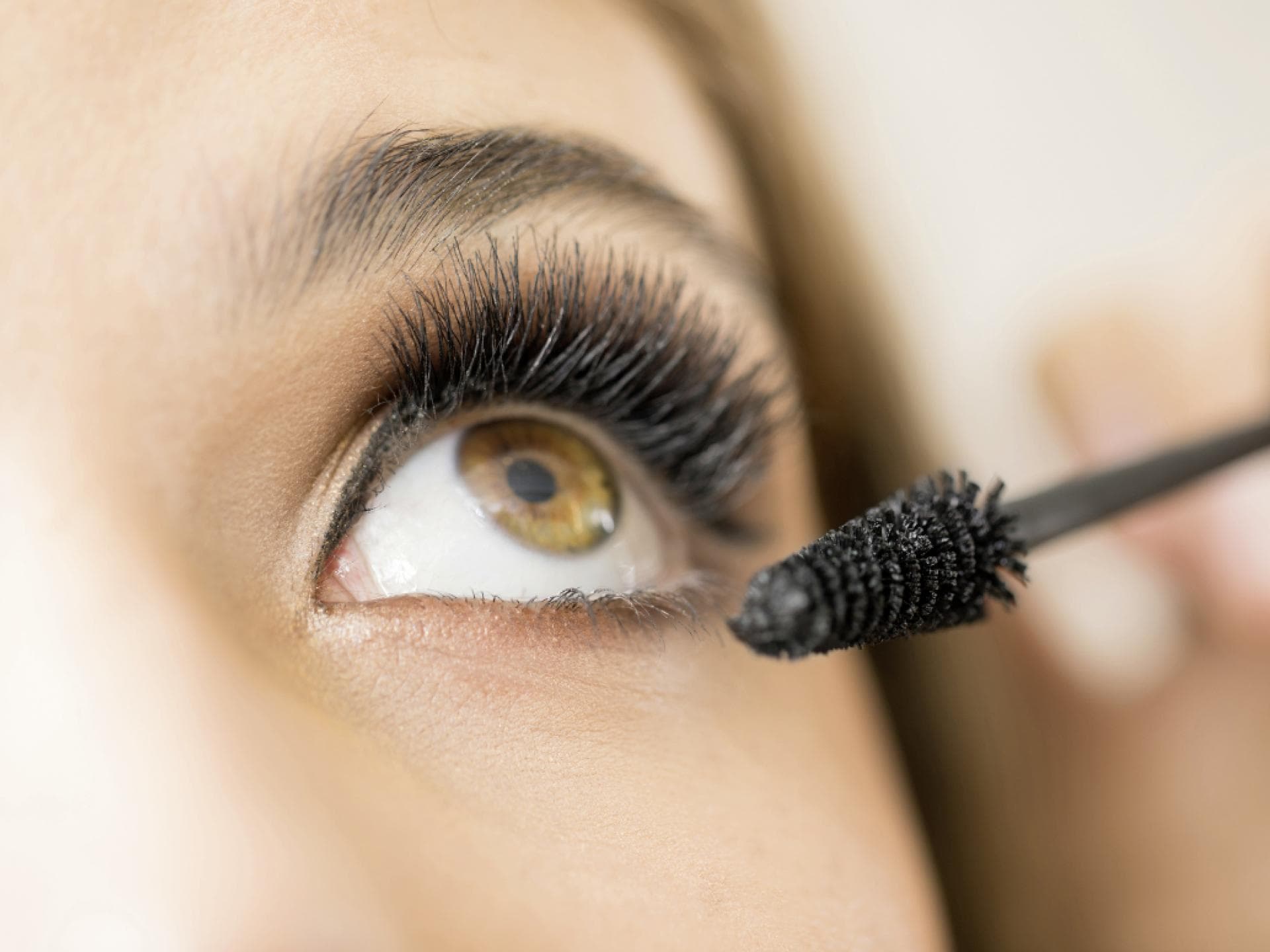 Frau trägt mascara für dichte Wimpern auf