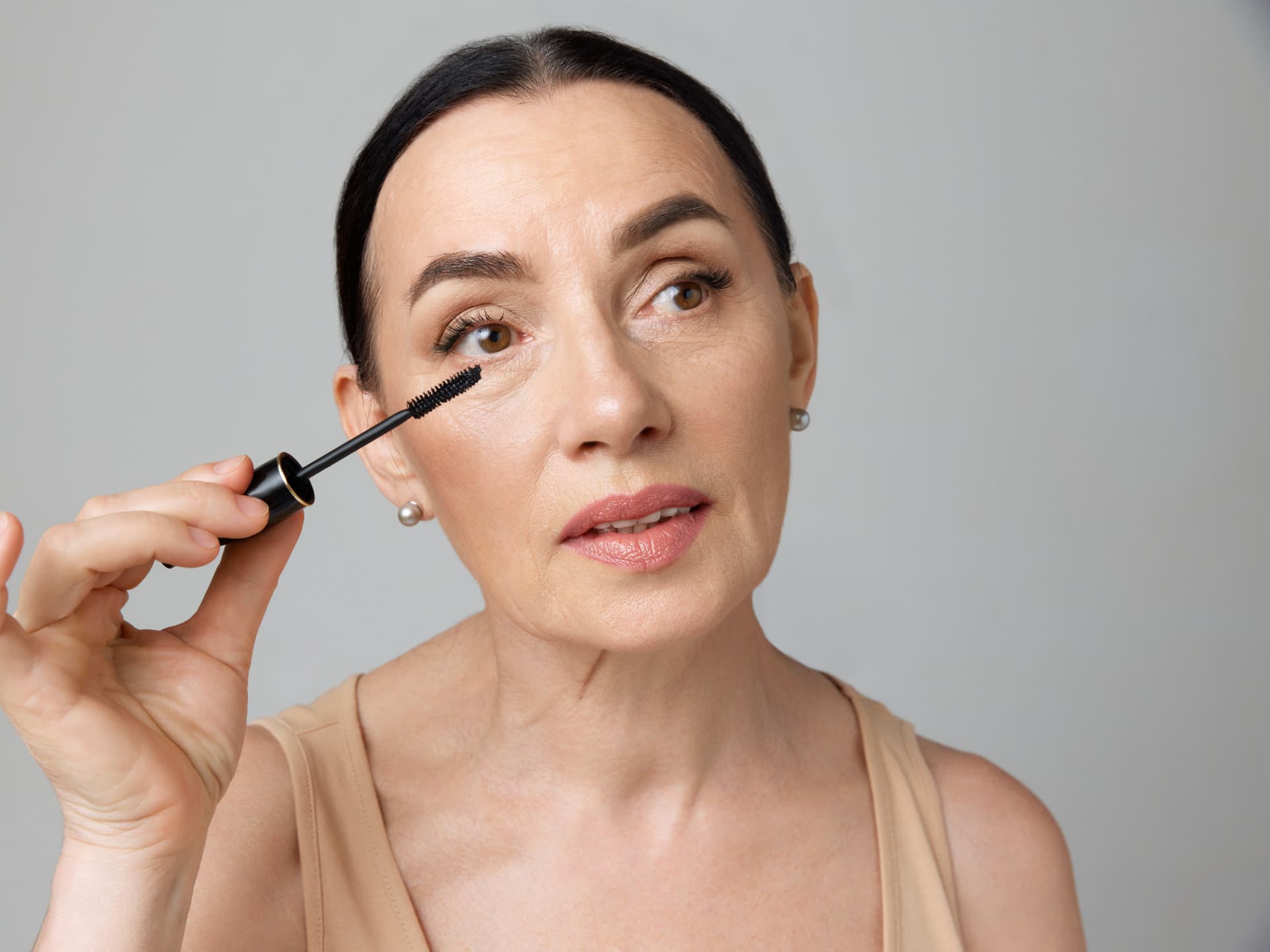 Frau trägt mit dem Mascara-Trick für Schlupflider Wimperntusche auf
