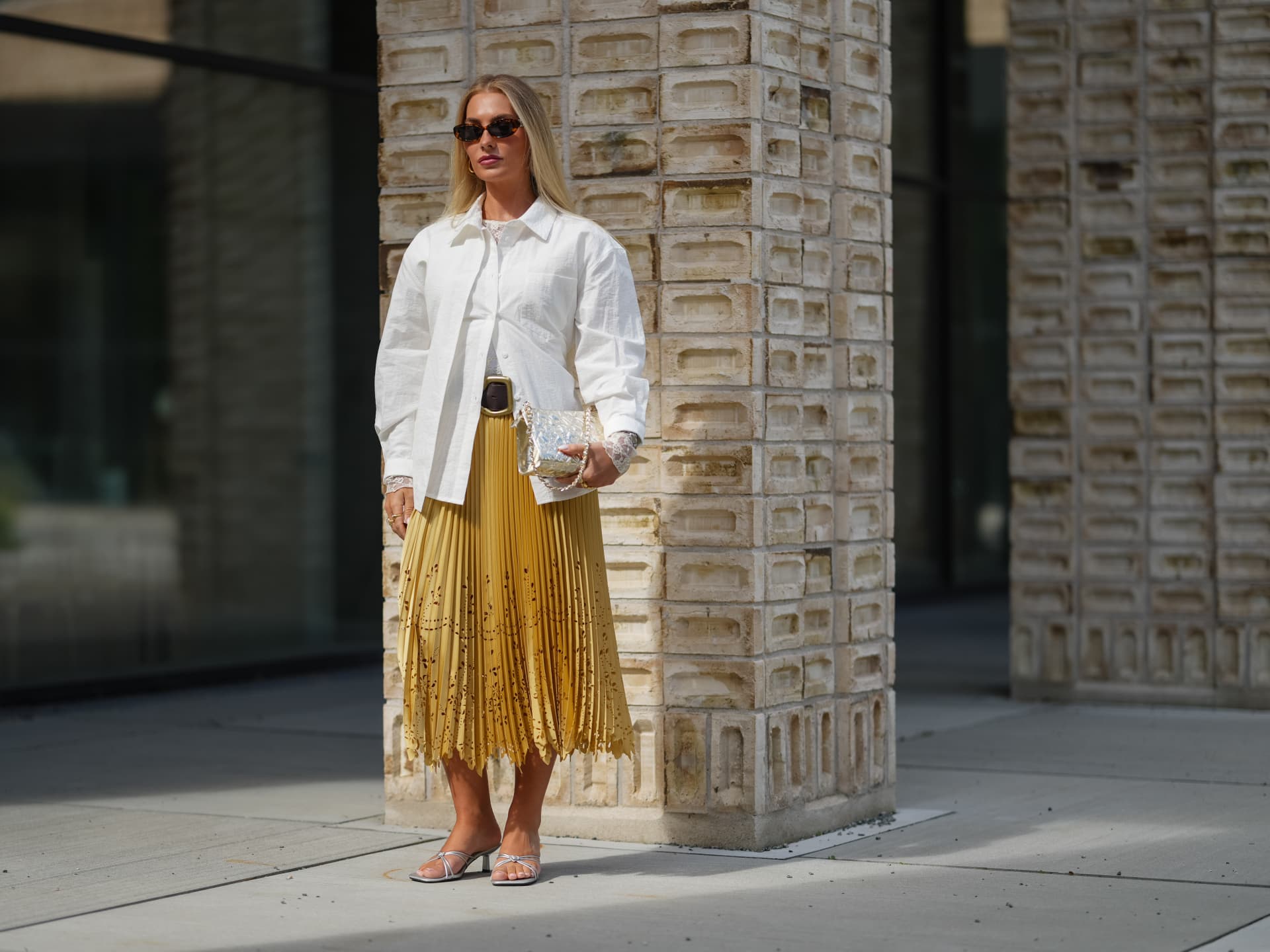 Eine Besucherin der Kopenhagen Fashion Week kombiniert silberne Sandalen zum Faltenrock