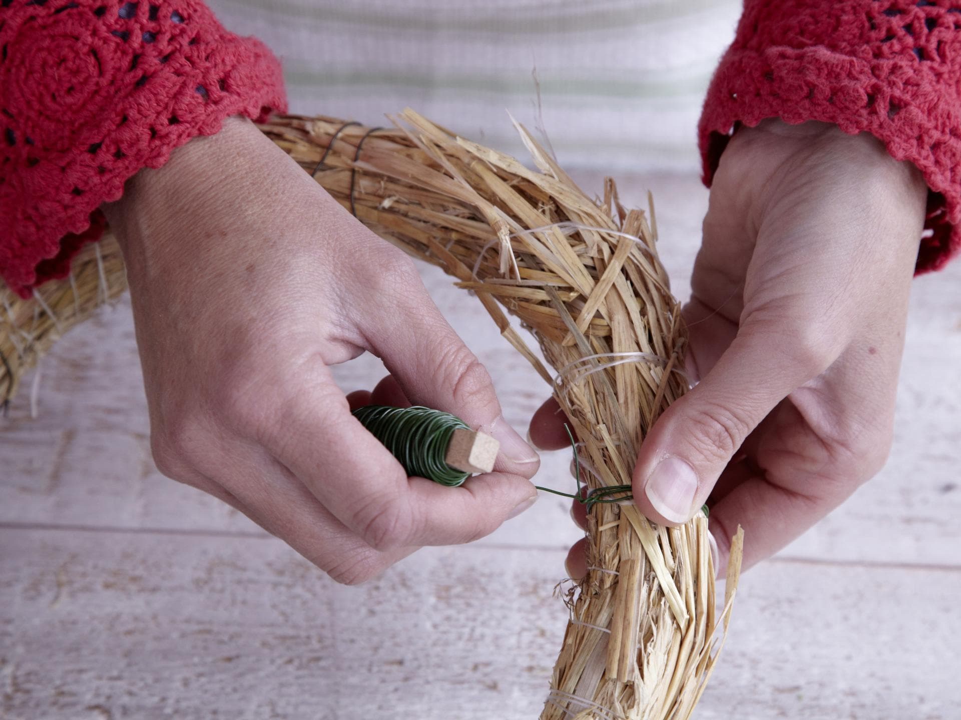 Adventskranz binden Frau wickelt Draht
