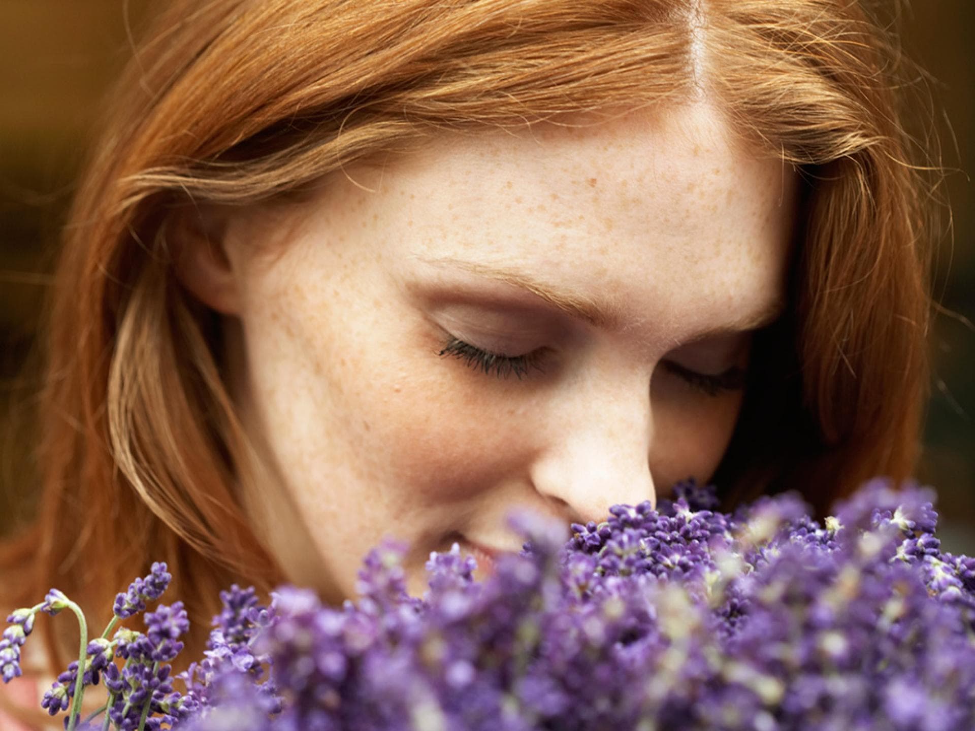 Frau riecht an heilenden Blumen - So lindern Ringelblume, Lavendel und Arnika Ihre Beschwerden