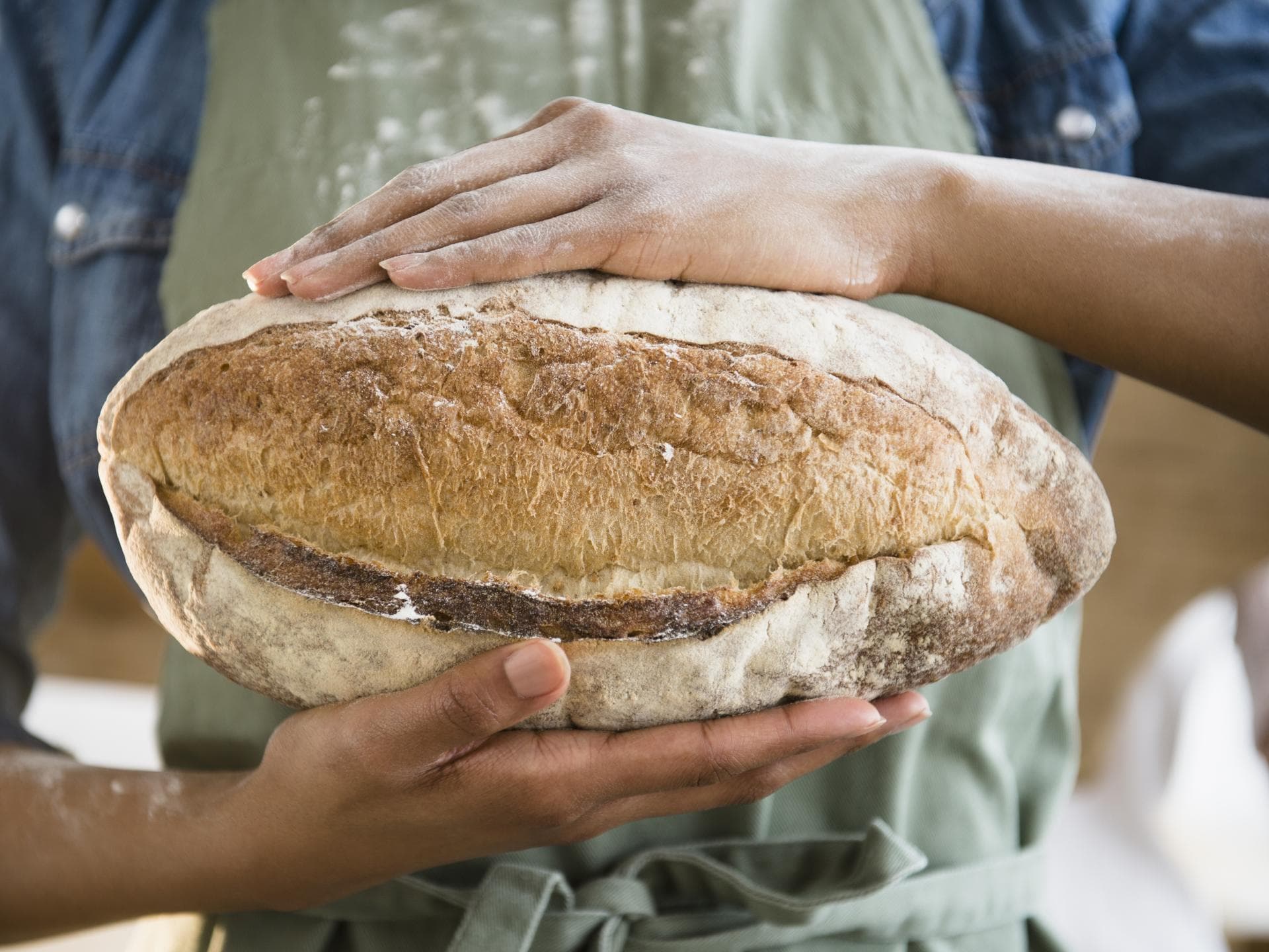 Frau hält selbstgebackenes Roggenbrot in den Händen - Das Backrezept gibt es hier