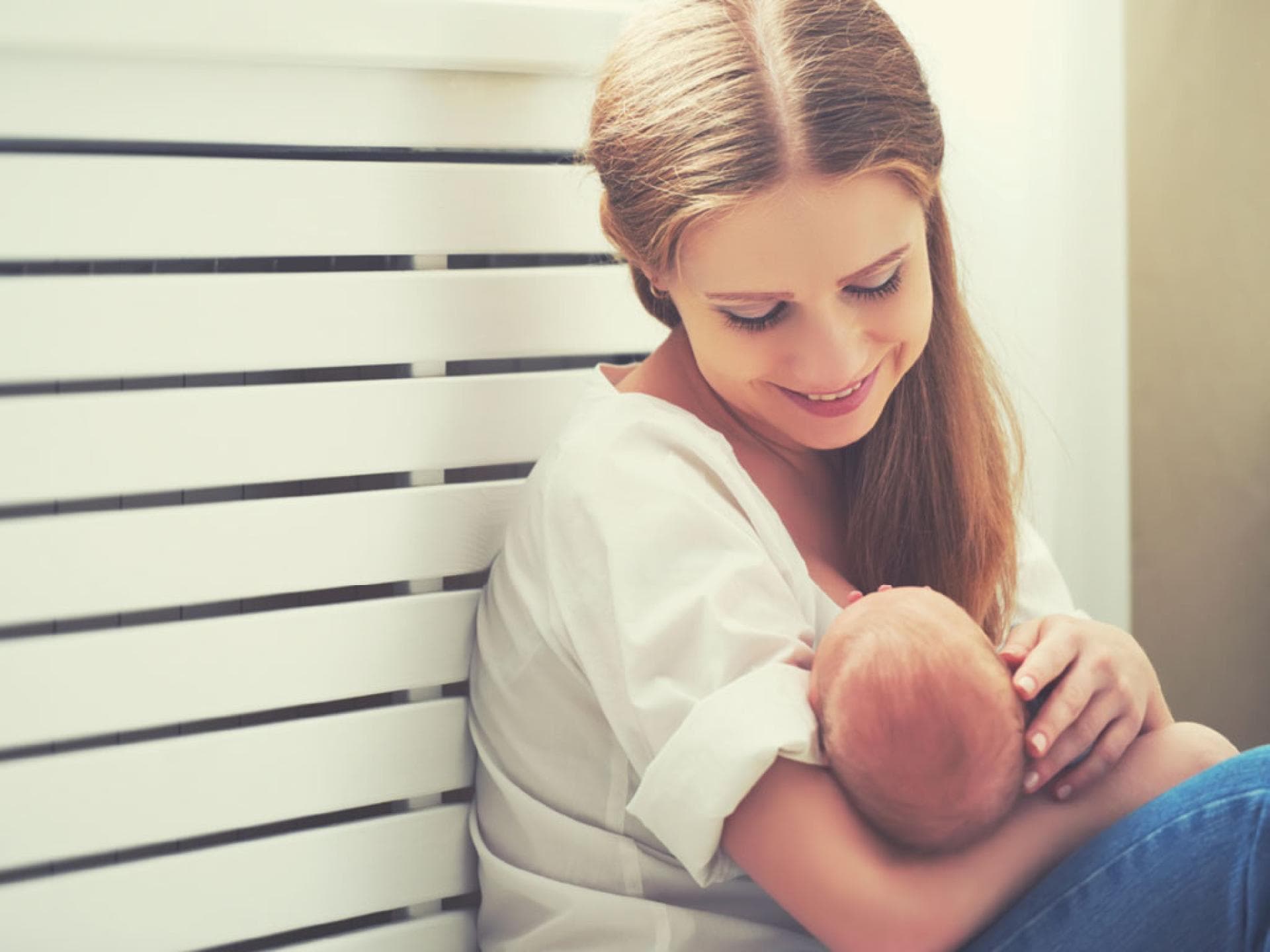 Junge Mutter mit Baby Junge Mutter hält ihr Baby in Fütterposition