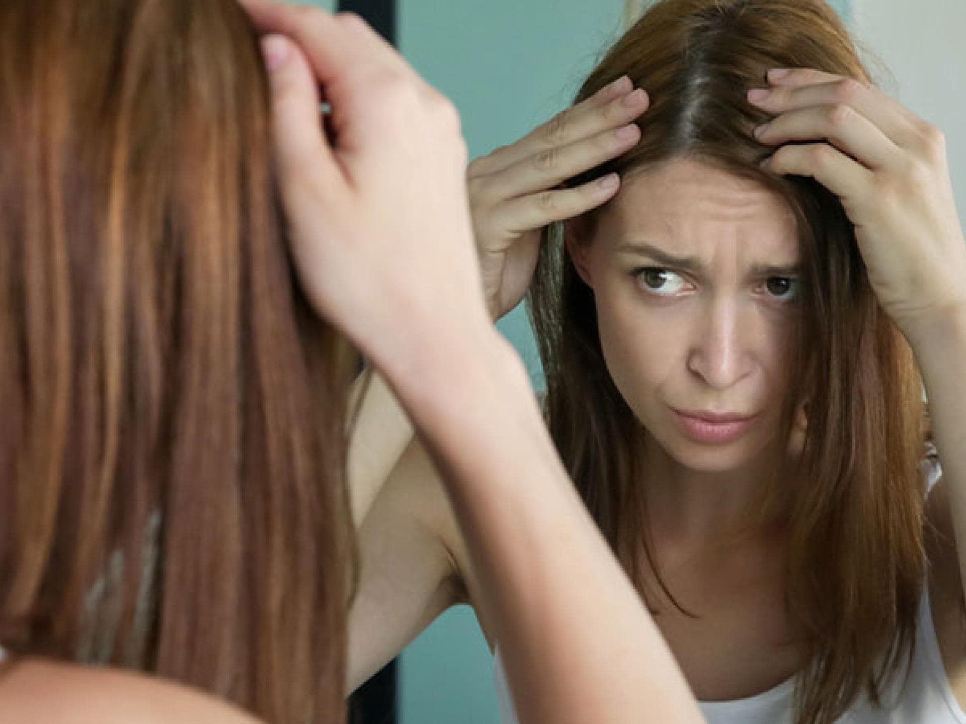 Frau prüft graue Haare – graue Haare durch Stress