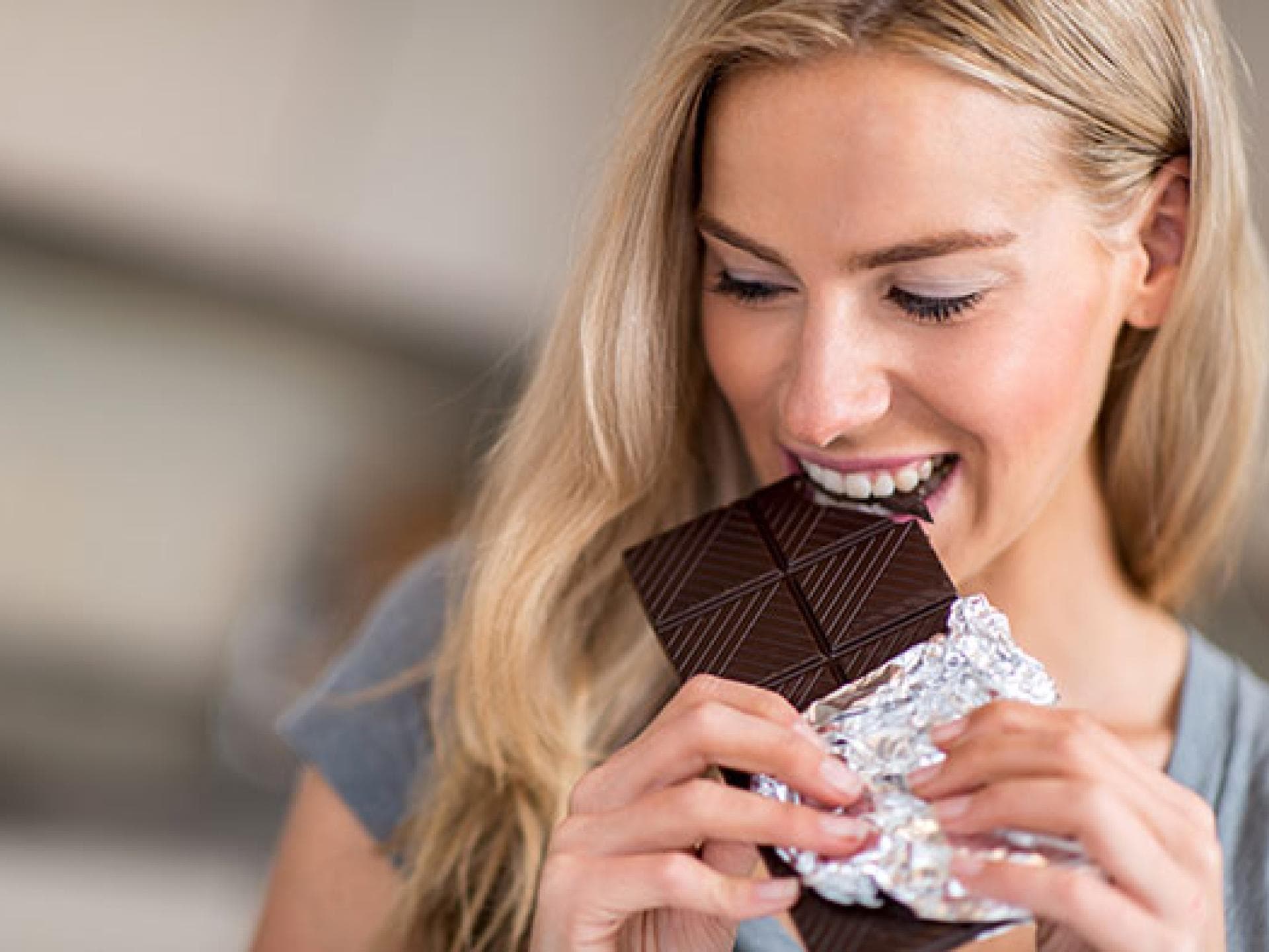 Frau isst Schokolade - ist Zucker ungesund für die Haut?