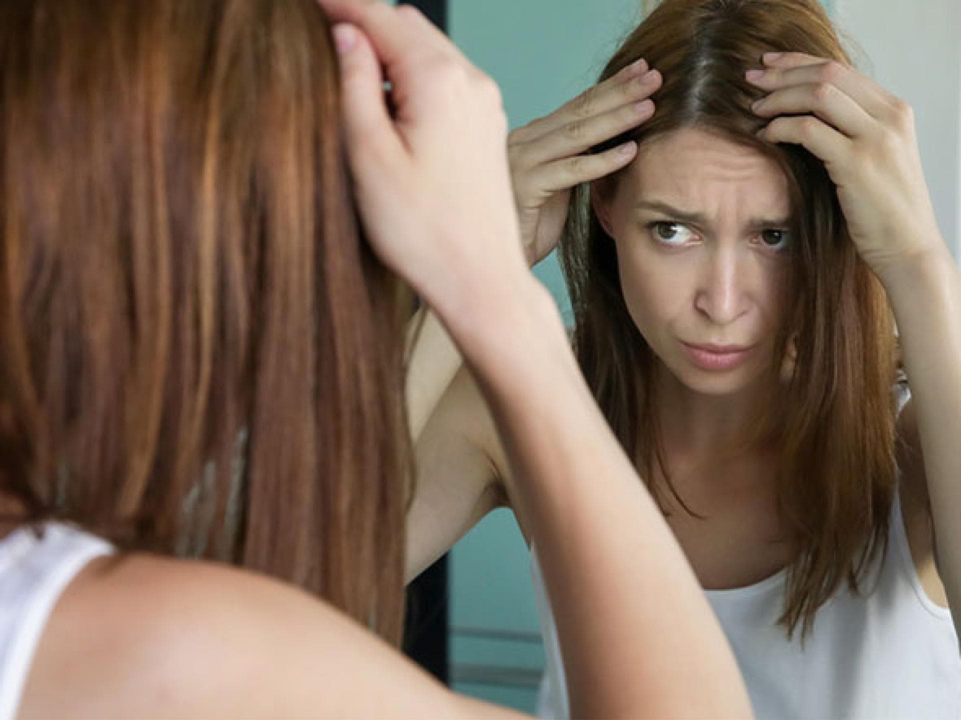 Frau prüft graue Haare – graue Haare durch Stress