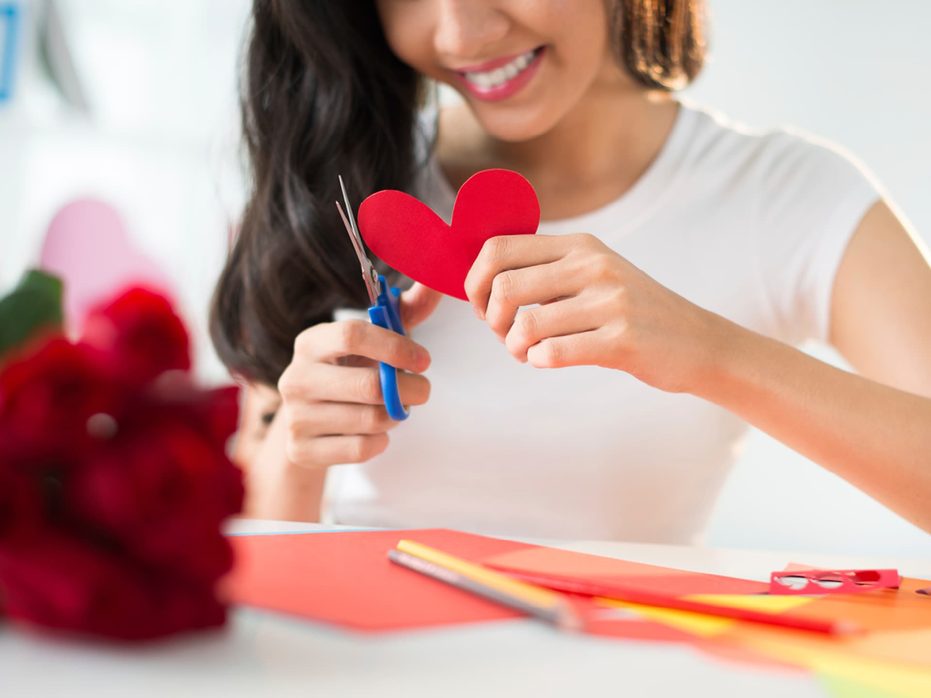 Eine Frau schneiden aus rotem Papier kleine Herzen aus Entdecken Sie unsere tollen DIY-Ideen für die Hochzeit!