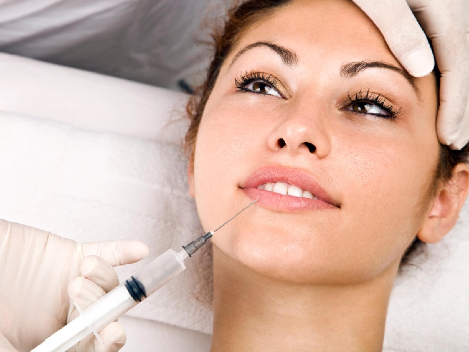 Frau bekommt auf einem Arztstuhl Botox gespritzt
