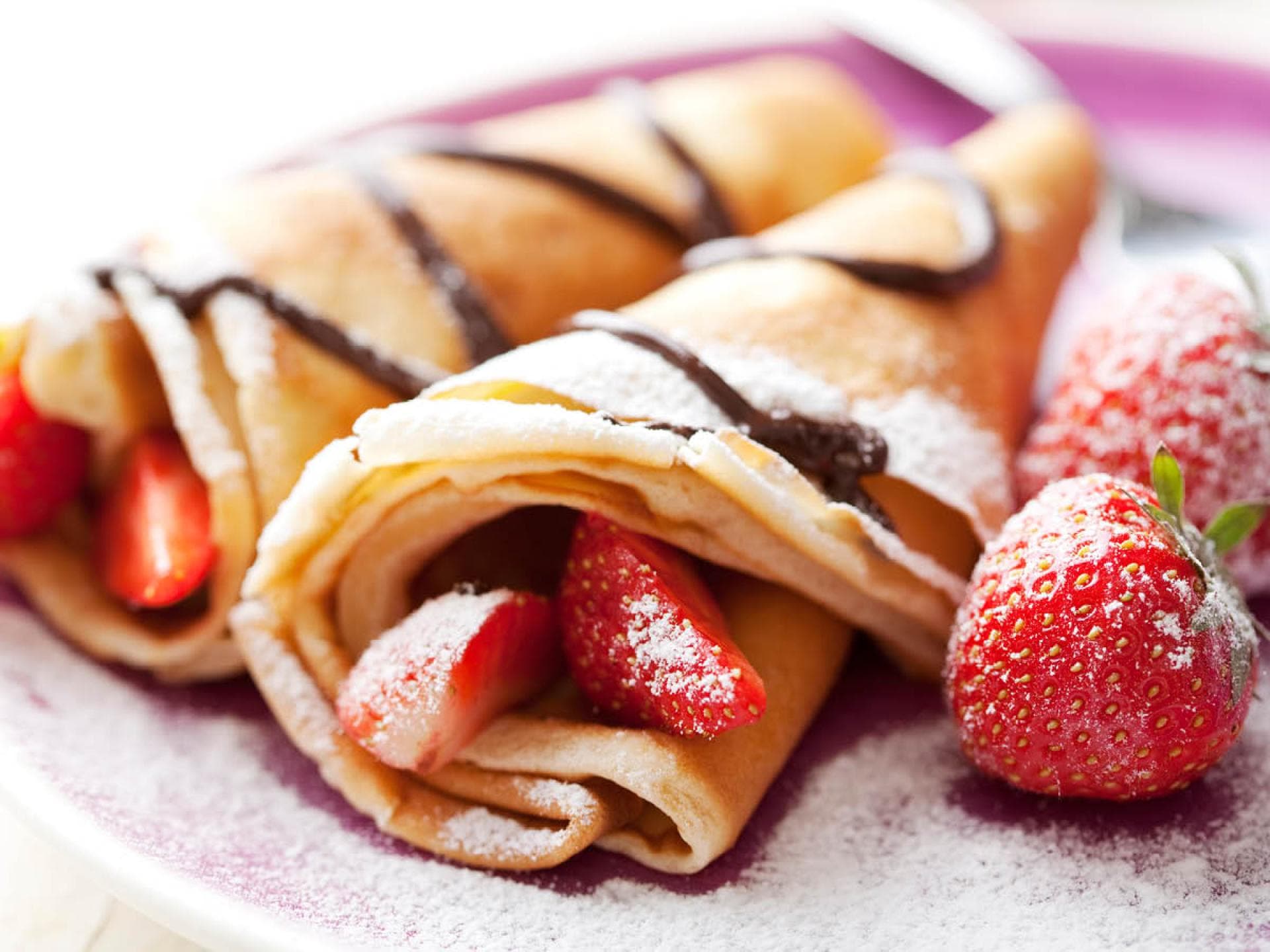 Eierkuchen Eierkuchen mit Schokolade, Puderzucker und Erdbeeren