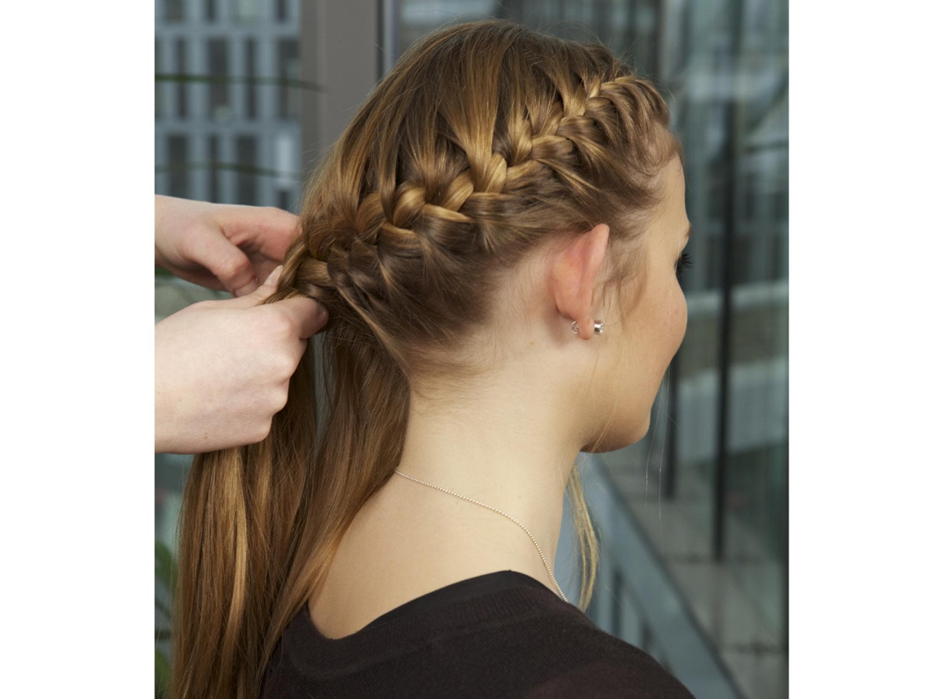 Frau flechtet einer Frau die Haare