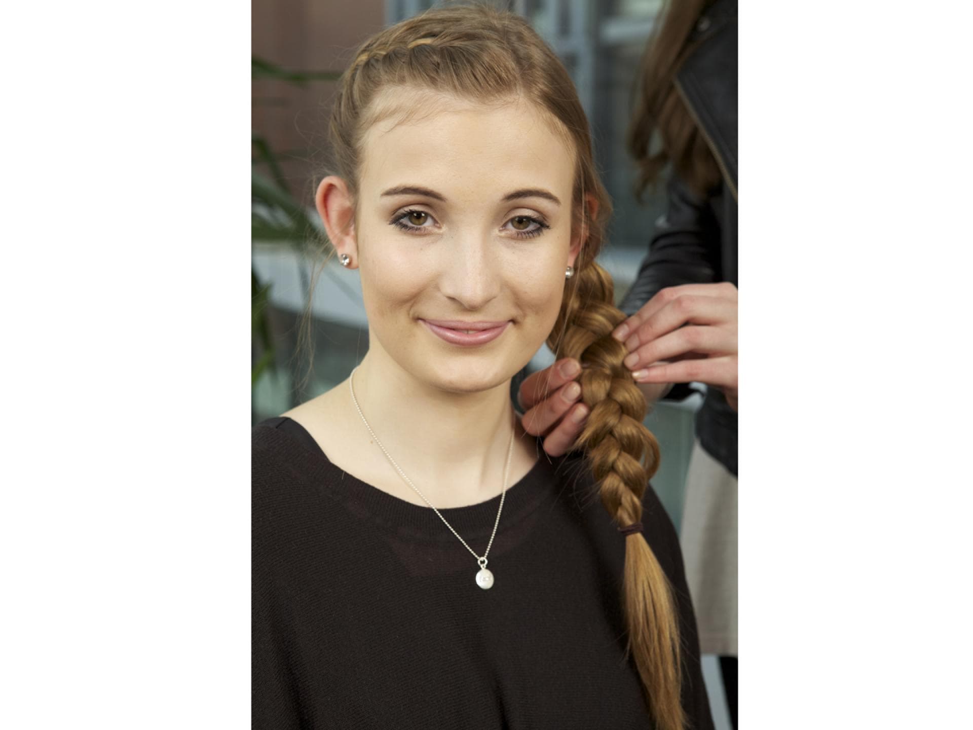 Haare werden aus dem Zopf einer Frau gezupft