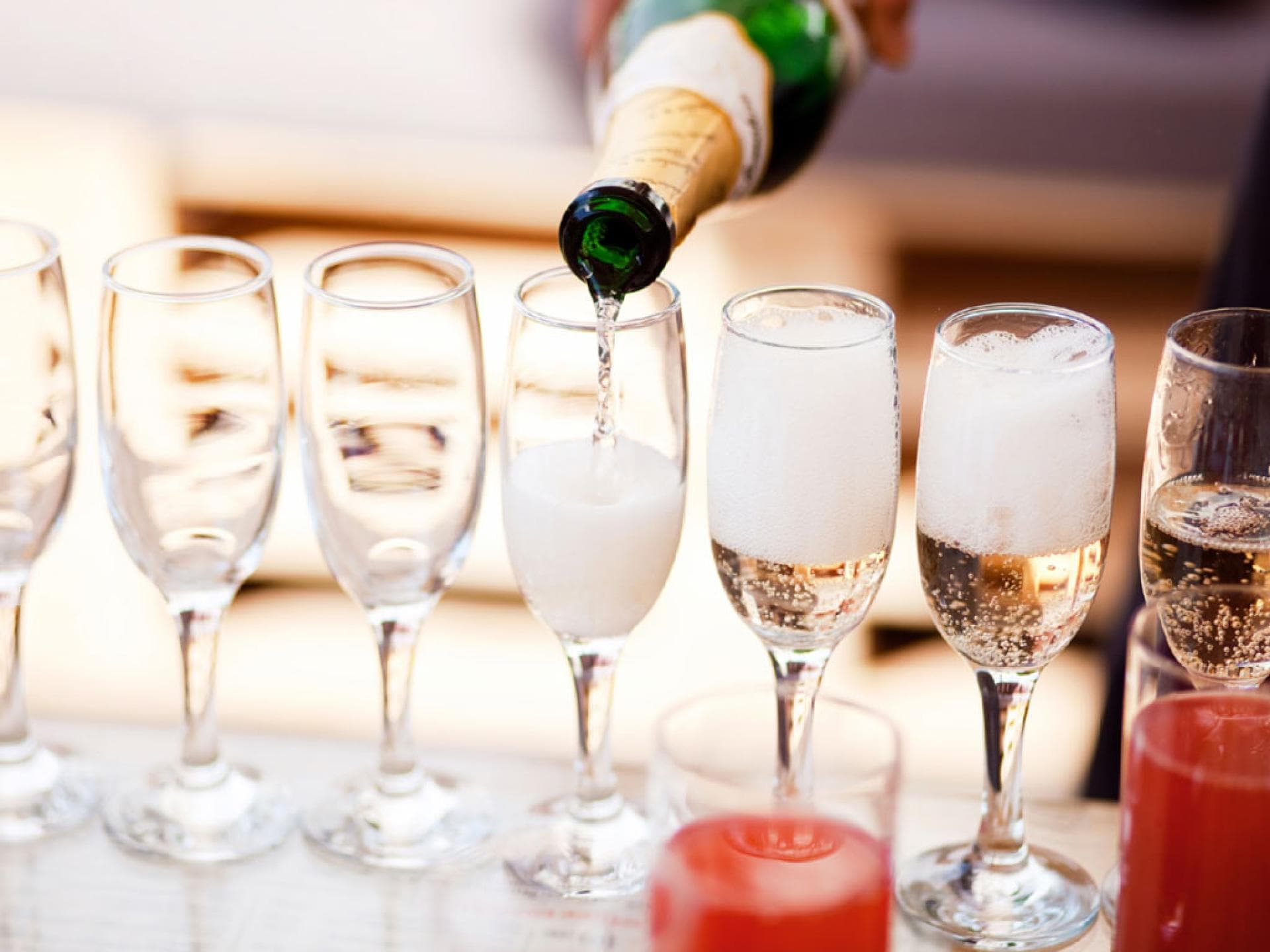 Eingießen von Sekt aus Sektflasche in mehrere Sektgläser