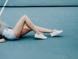 Frau mit nackten Beinen auf Tennisplatz