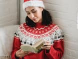 Frau mit Weihnachtsmütze liest Weihnachtsroman.