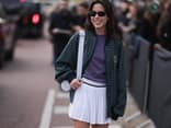 Frau mit Sonnenbrille, Collegejacke und Tennisrock