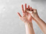 Die rechte Hand fasst an den linken Mittelfinger