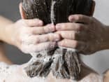 Frau wäscht Haare unter der Dusche