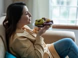 Frau hält einen Teller mit Donuts vor ihr Gesicht